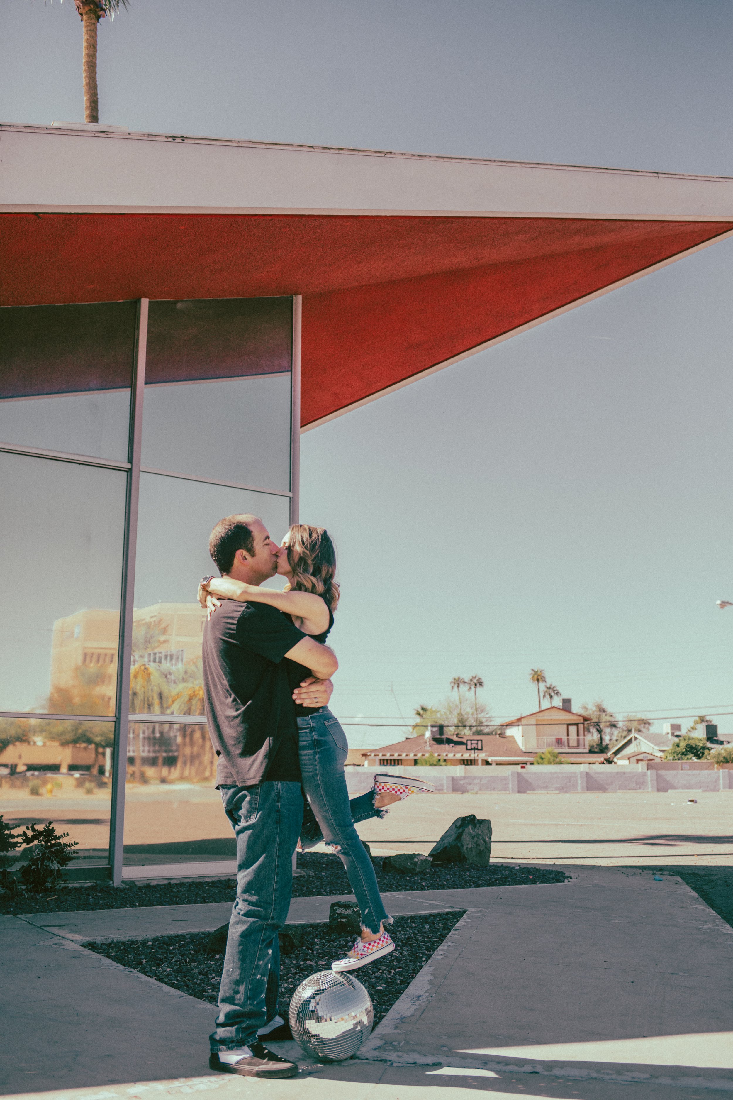 Couple poses for their retro bike and skateboard photoshoot at Bowlero in Phoenix, Arizona by creative family photographer; Jennifer Lind Schutsky.