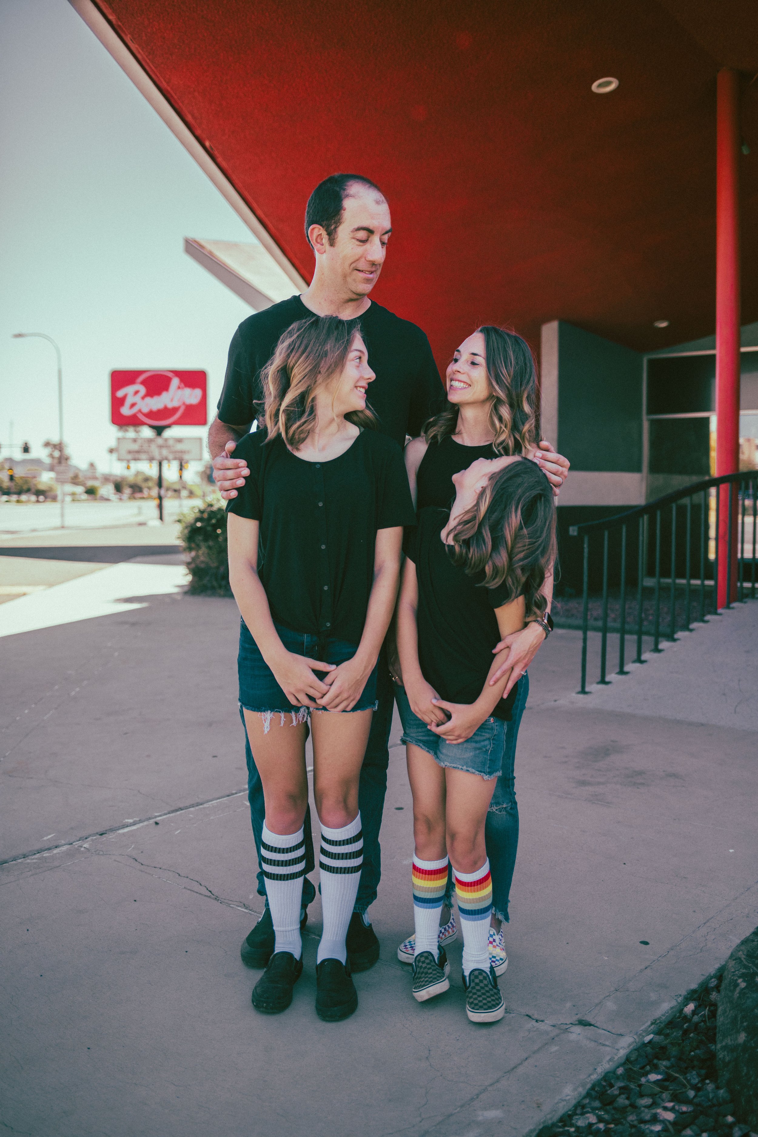 Family poses for retro bike and skateboard photoshoot at Bowlero in Phoenix, Arizona by creative family photographer; Jennifer Lind Schutsky.