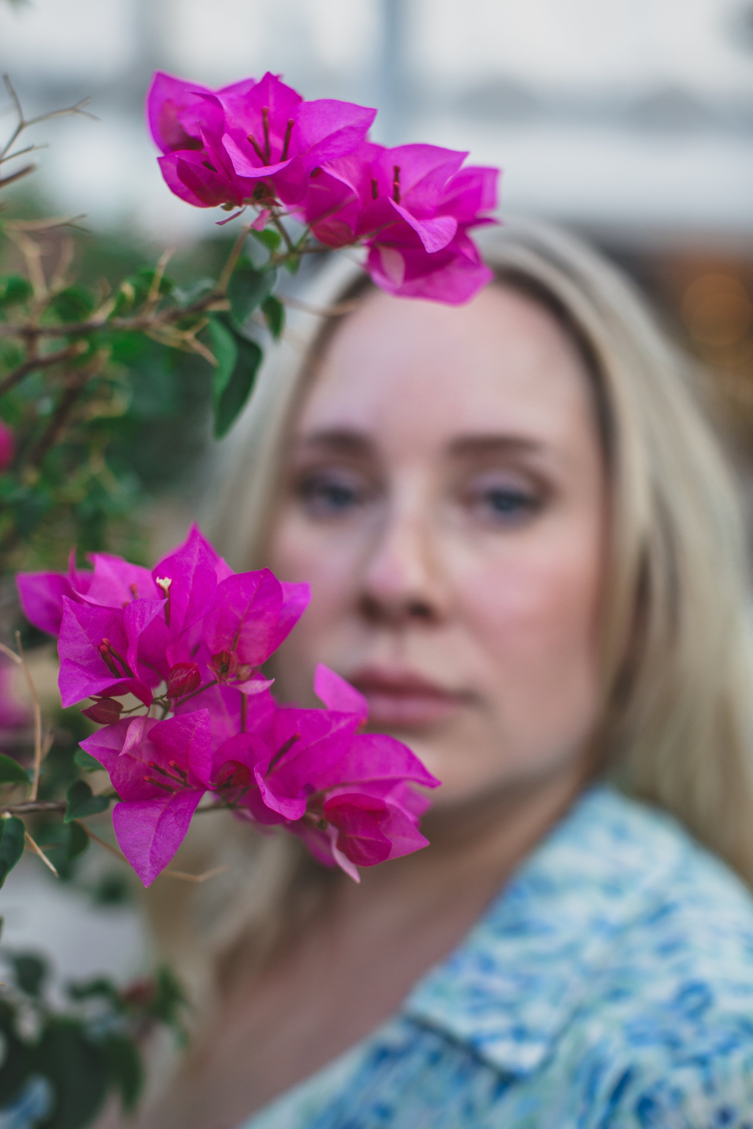 Woman poses behind flowers for the #portraitproject by Creative Phoenix Photographer; Jennifer Lind Schutsky.