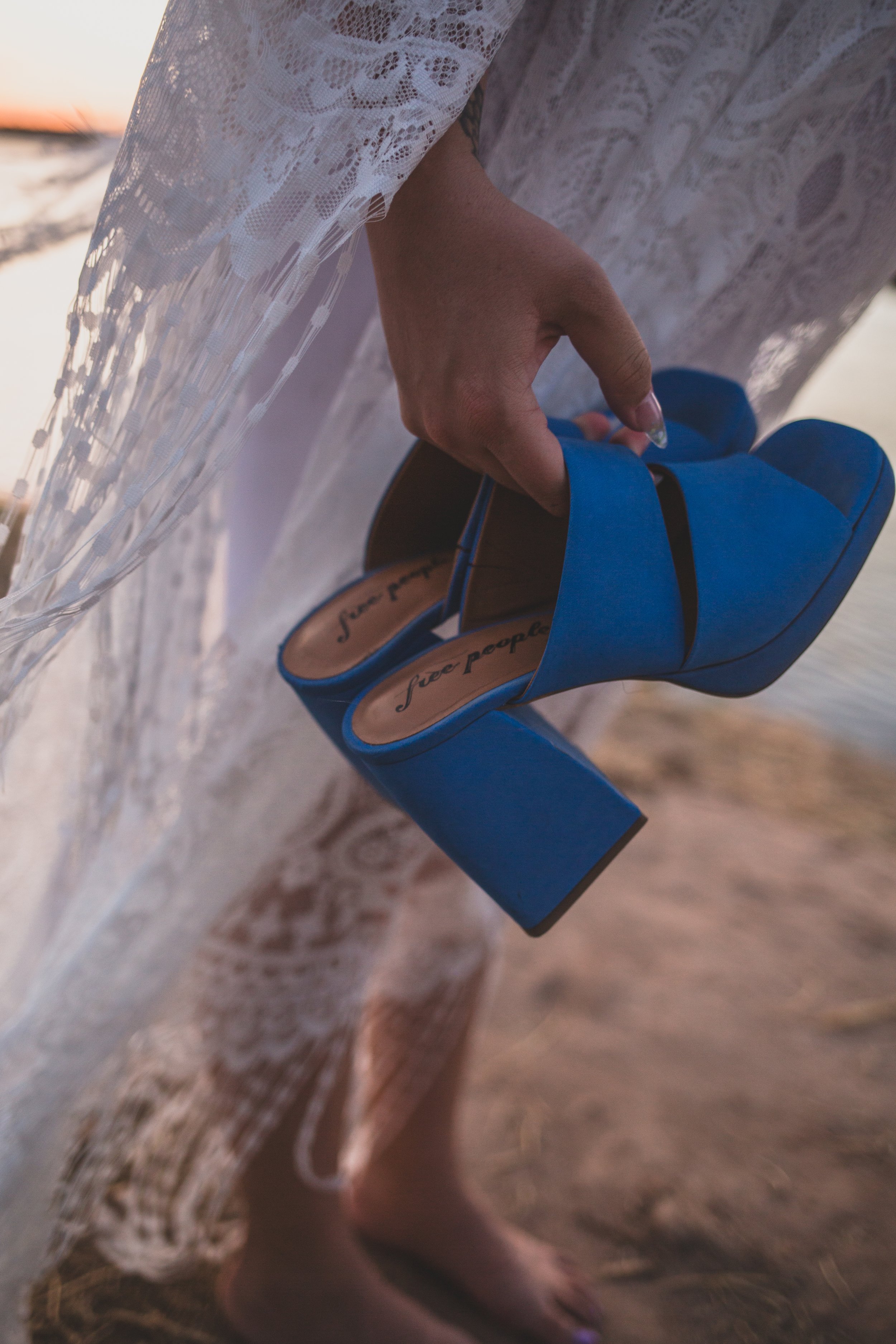 Details of shoes of pregnant mother posing for maternity photos near the water at sunset the Salt River by timeless Phoenix maternity photographer; Jennifer Lind Schutsky.