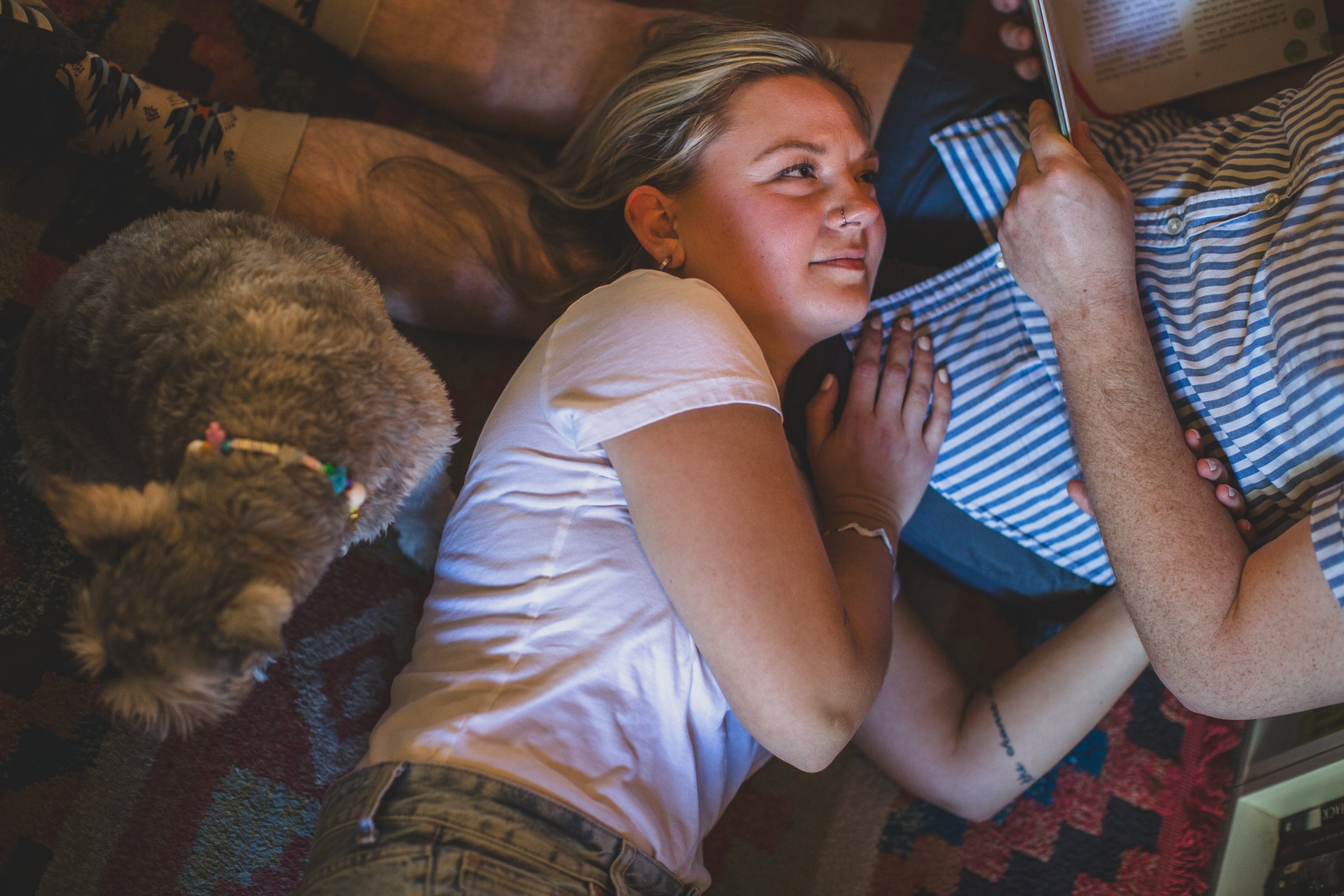 Newly engaged couple cuddles with their dog on the floor during their In-Home Engagement Session with Phoenix based intimate engagement photographer Jennifer Lind Schutsky. 