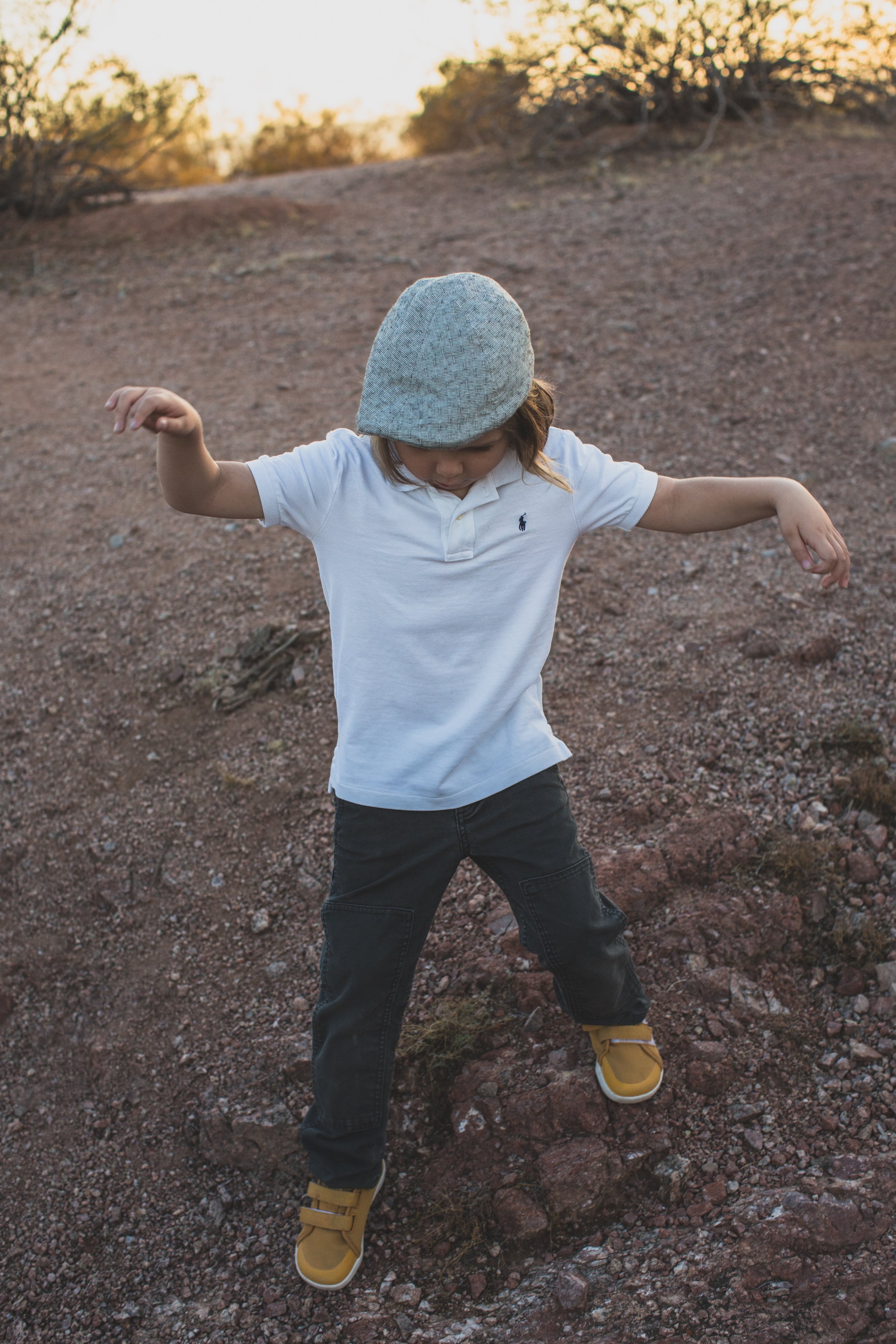 Stylish young kid poses while playing at his family desert photo session near Papago Park in Tempe, Arizona by Phoenix based family photographer Jennifer Lind Schutsky. 