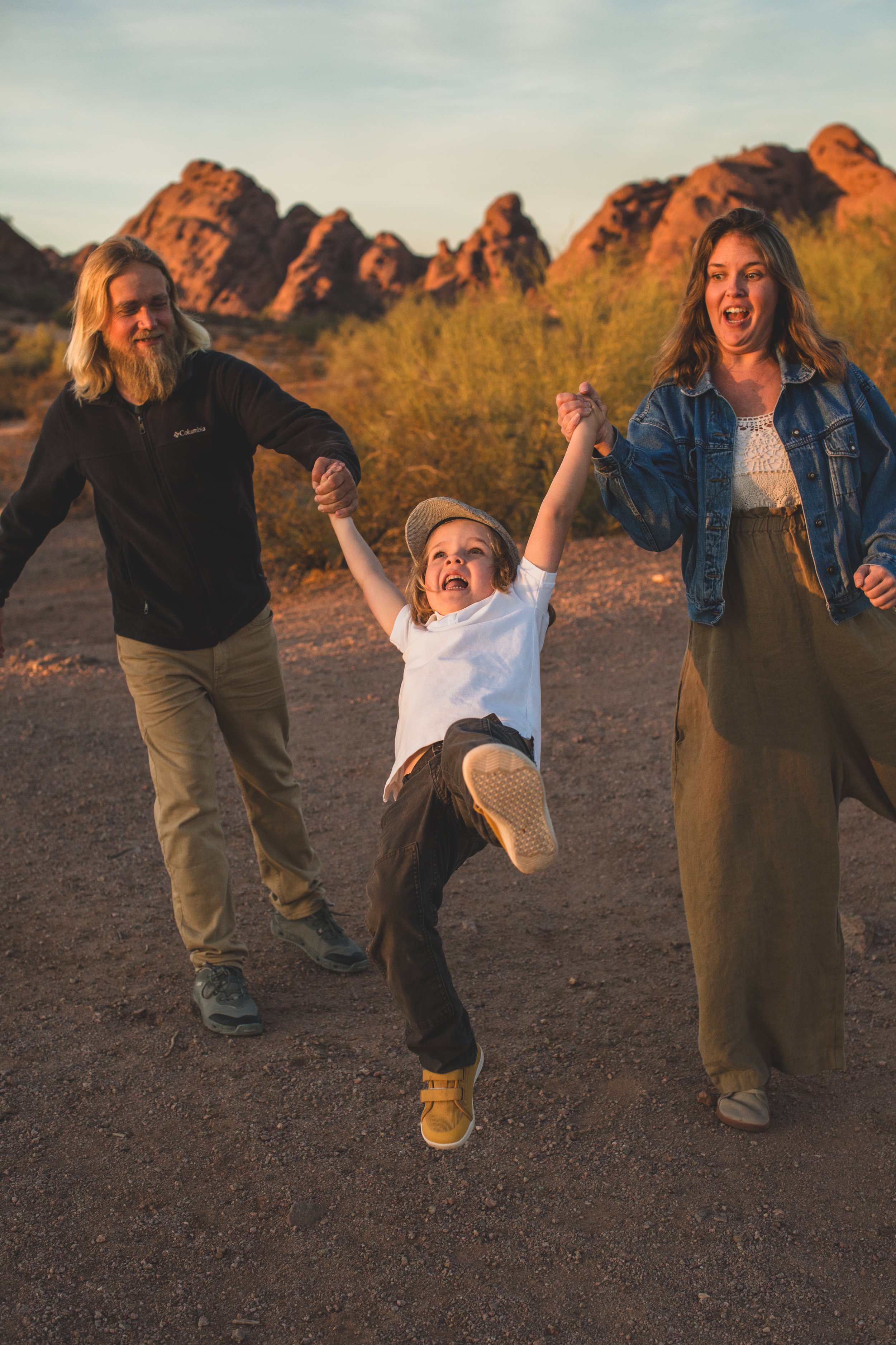 Casual dressed family plays together during family desert photo session near Papago Park in Tempe, Arizona by Phoenix based family photographer Jennifer Lind Schutsky. 