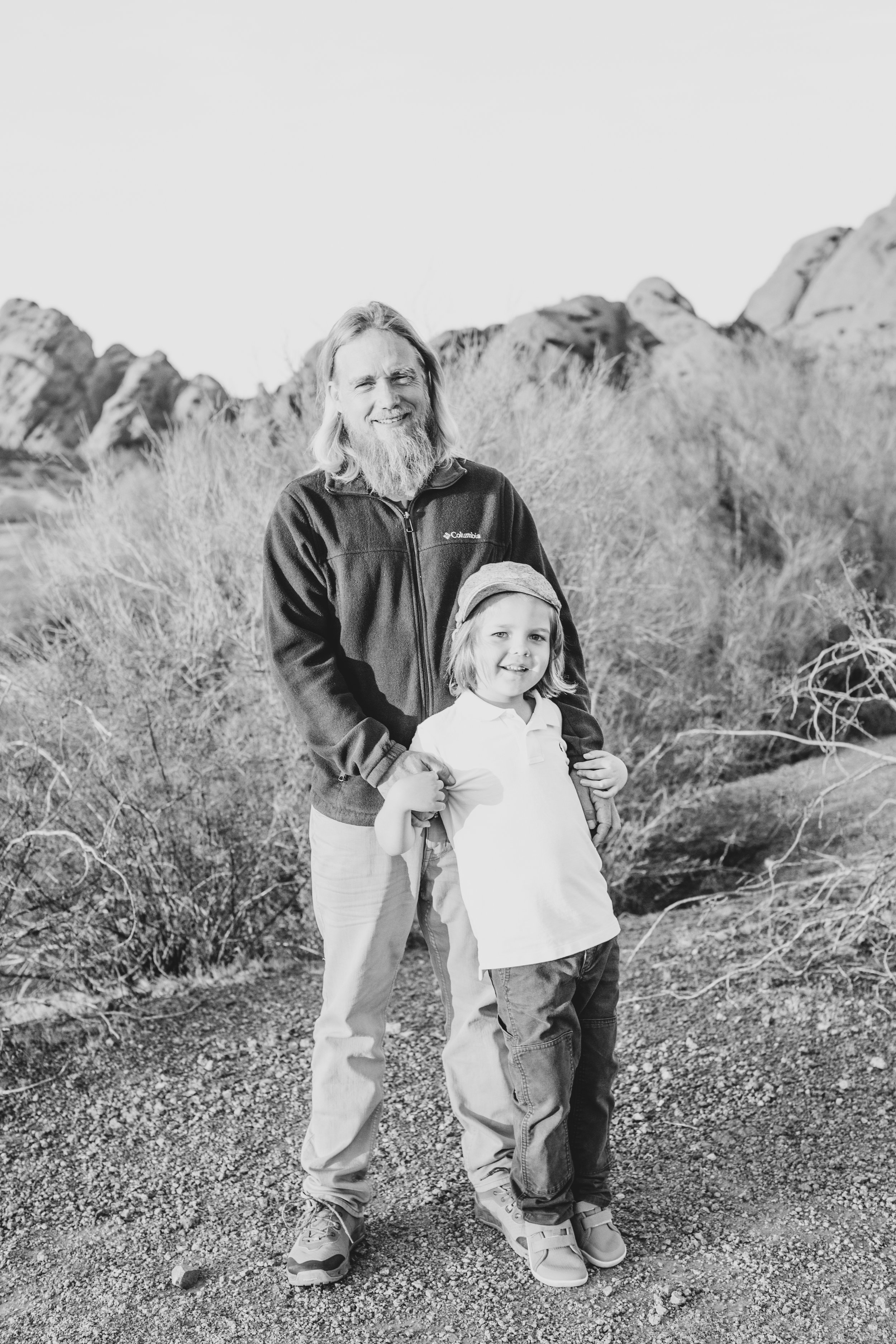 Casual dressed father and son pose together during family desert photo session near Papago Park in Tempe, Arizona by Phoenix based family photographer Jennifer Lind Schutsky. 
