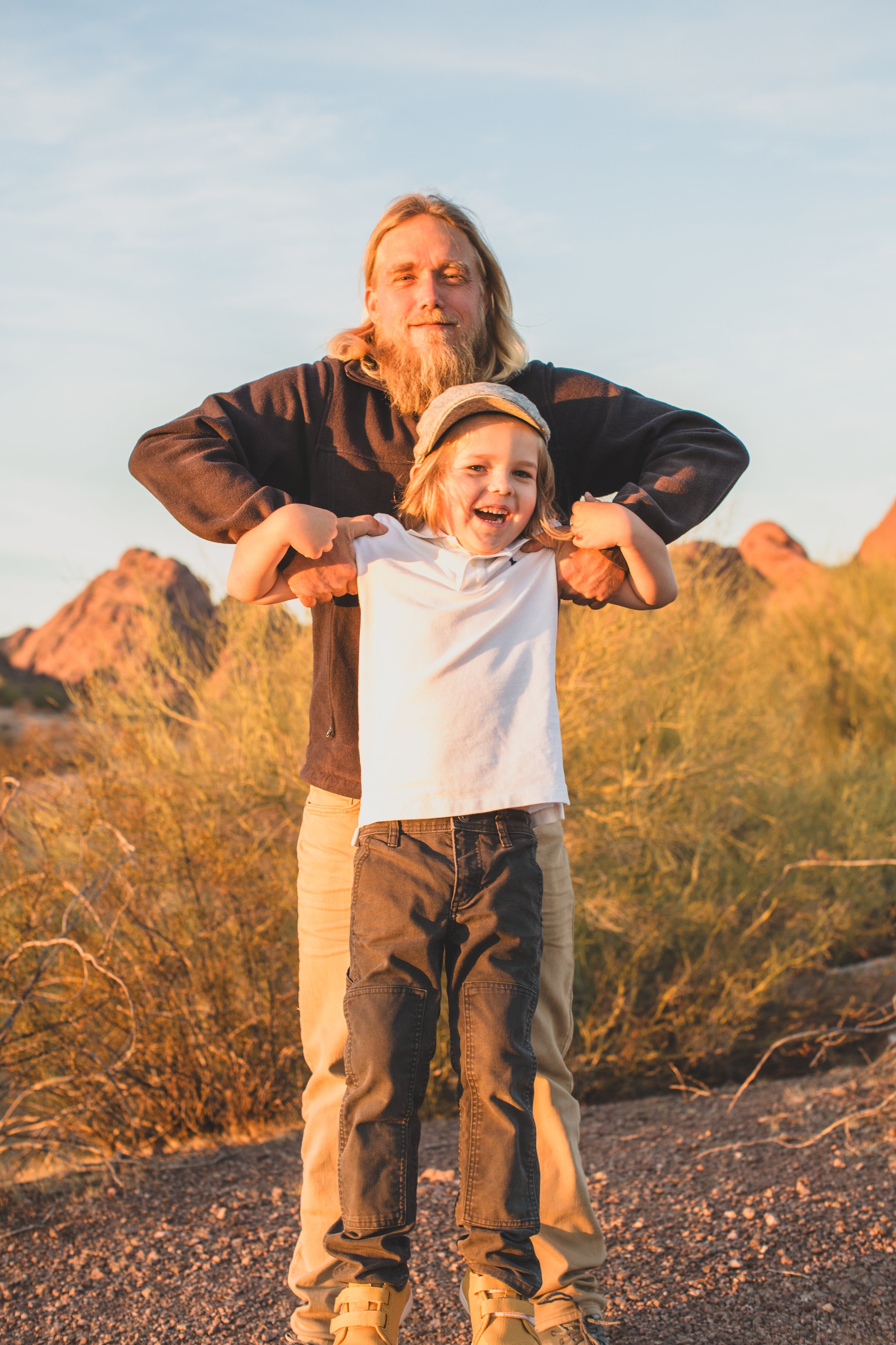 Casual dressed father and son pose together during family desert photo session near Papago Park in Tempe, Arizona by Phoenix based family photographer Jennifer Lind Schutsky. 