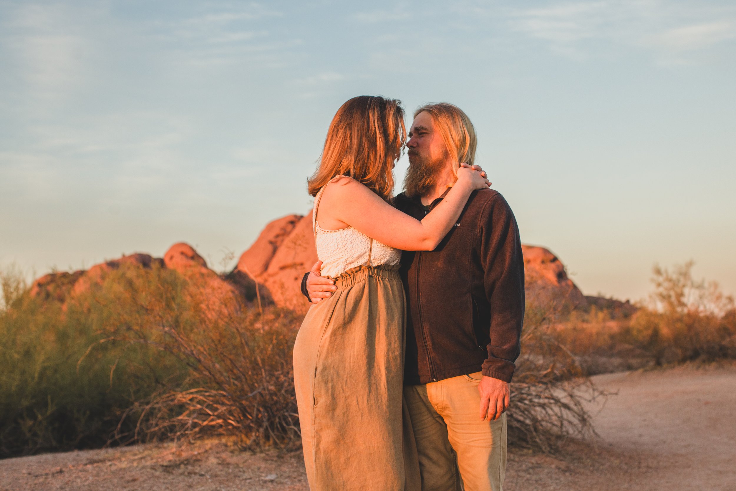 Mom and dad kiss during family desert photo session near Papago Park in Tempe, Arizona by Phoenix based family photographer Jennifer Lind Schutsky. 