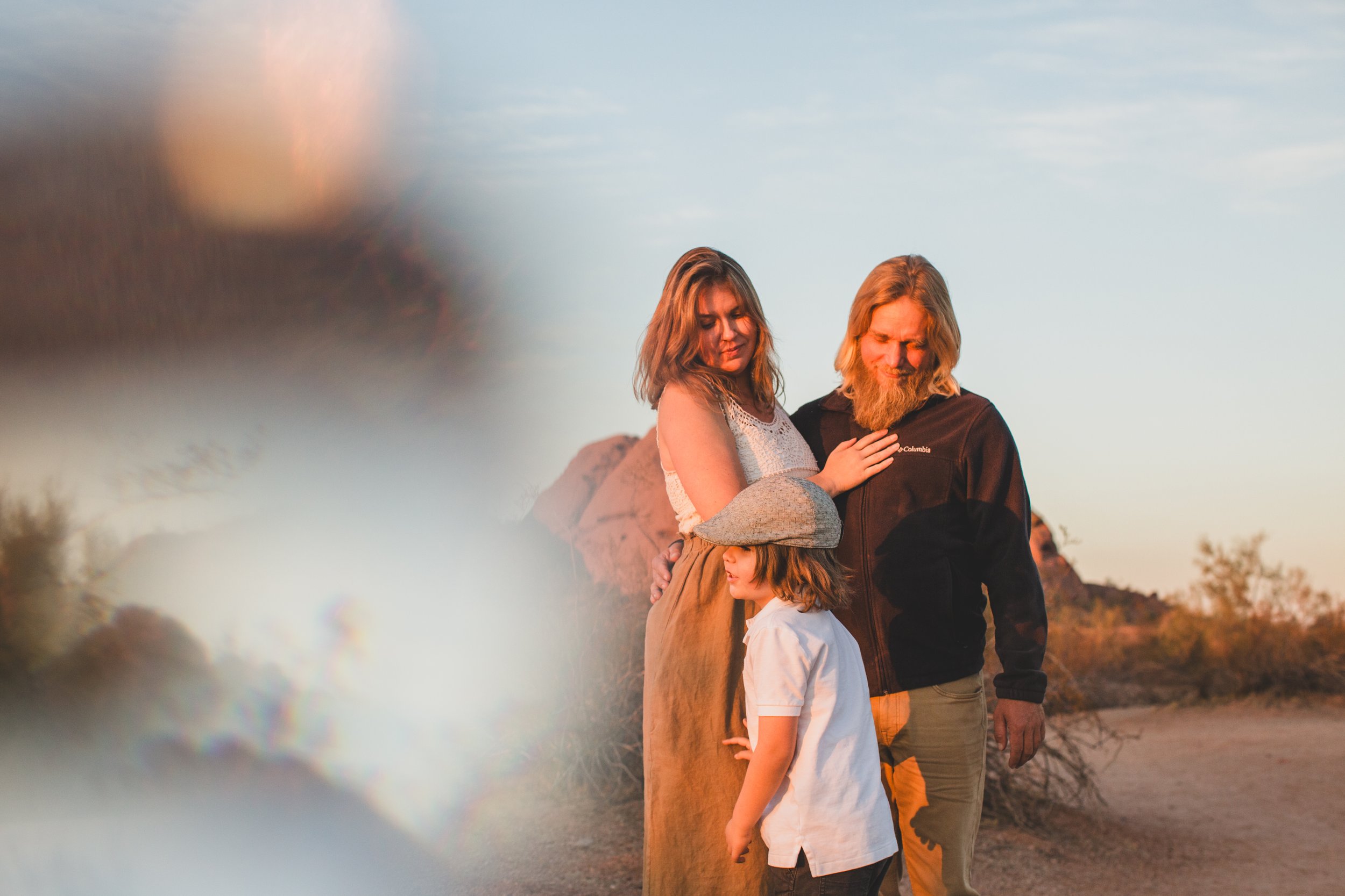Mom and dad hug during family desert photo session near Papago Park in Tempe, Arizona by Phoenix based family photographer Jennifer Lind Schutsky. 