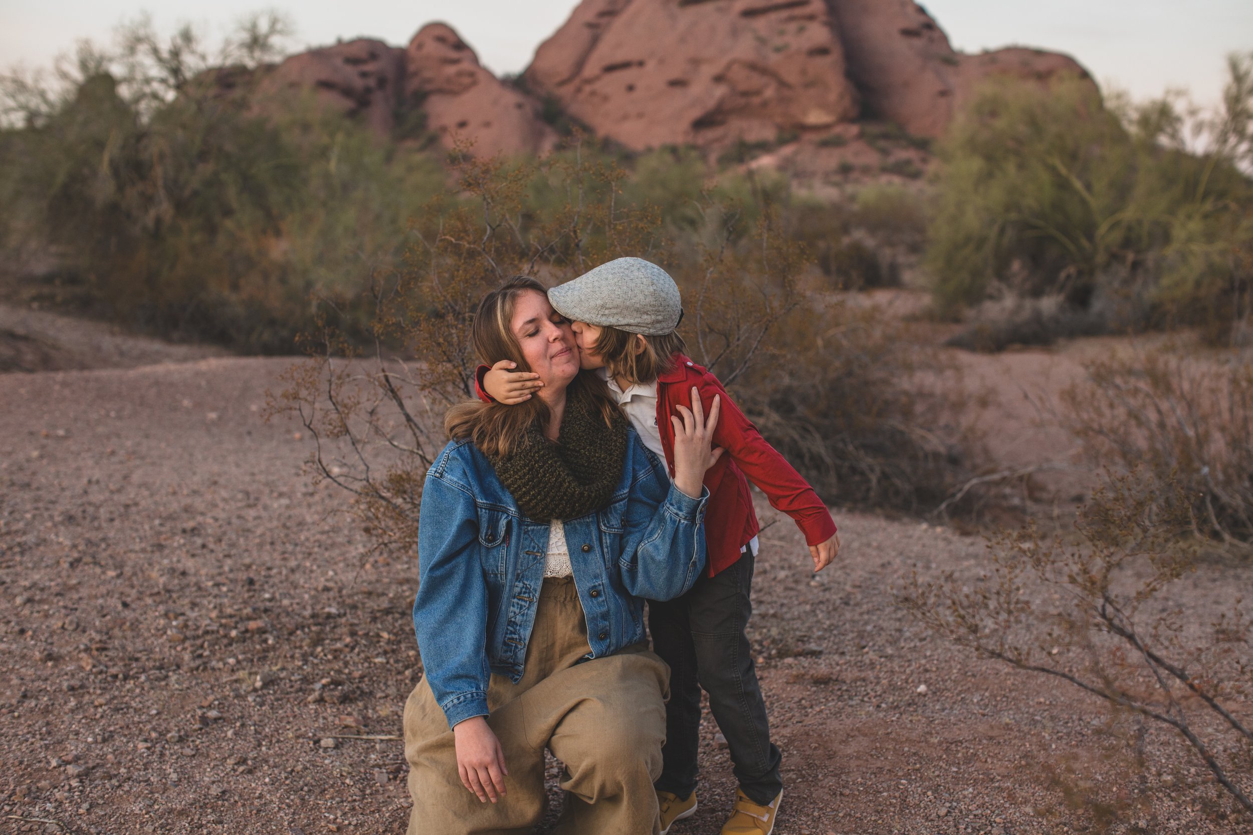 Well dressed little boy hugs mom while playing at his family desert photo session near Papago Park in Tempe, Arizona by Phoenix based family photographer Jennifer Lind Schutsky. 