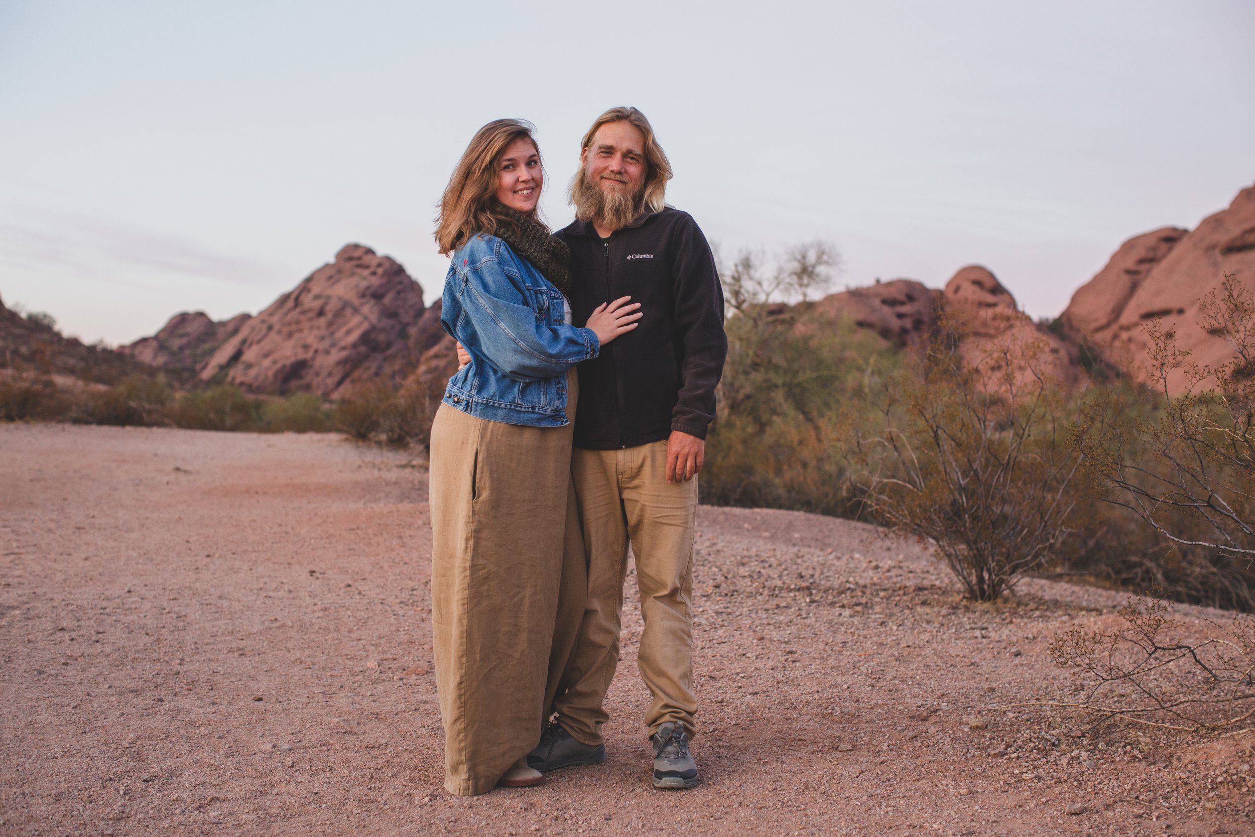Mom and dad pose for photo by son at family desert photo session near Papago Park in Tempe, Arizona by Phoenix based family photographer Jennifer Lind Schutsky. 