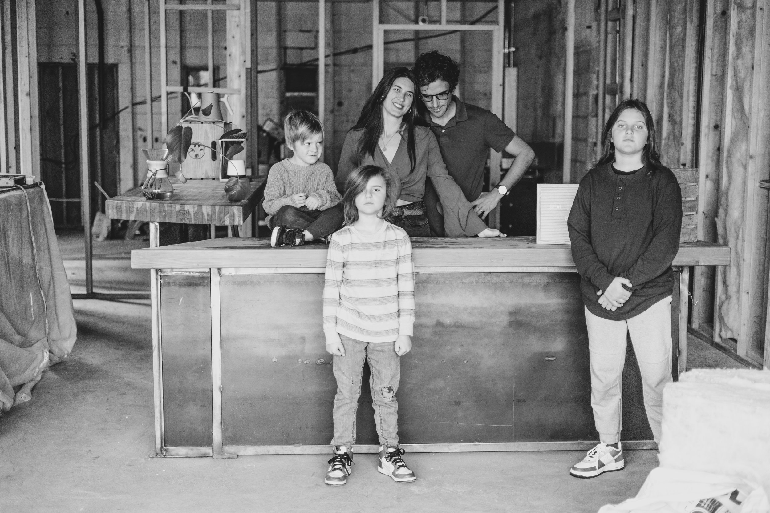 Family poses for their unique photo session in the unfinished Beal Beans’ new coffee shop coming to Sunnyslope, AZ by Arizona family photographer, Jennifer Lind Schutsky. 