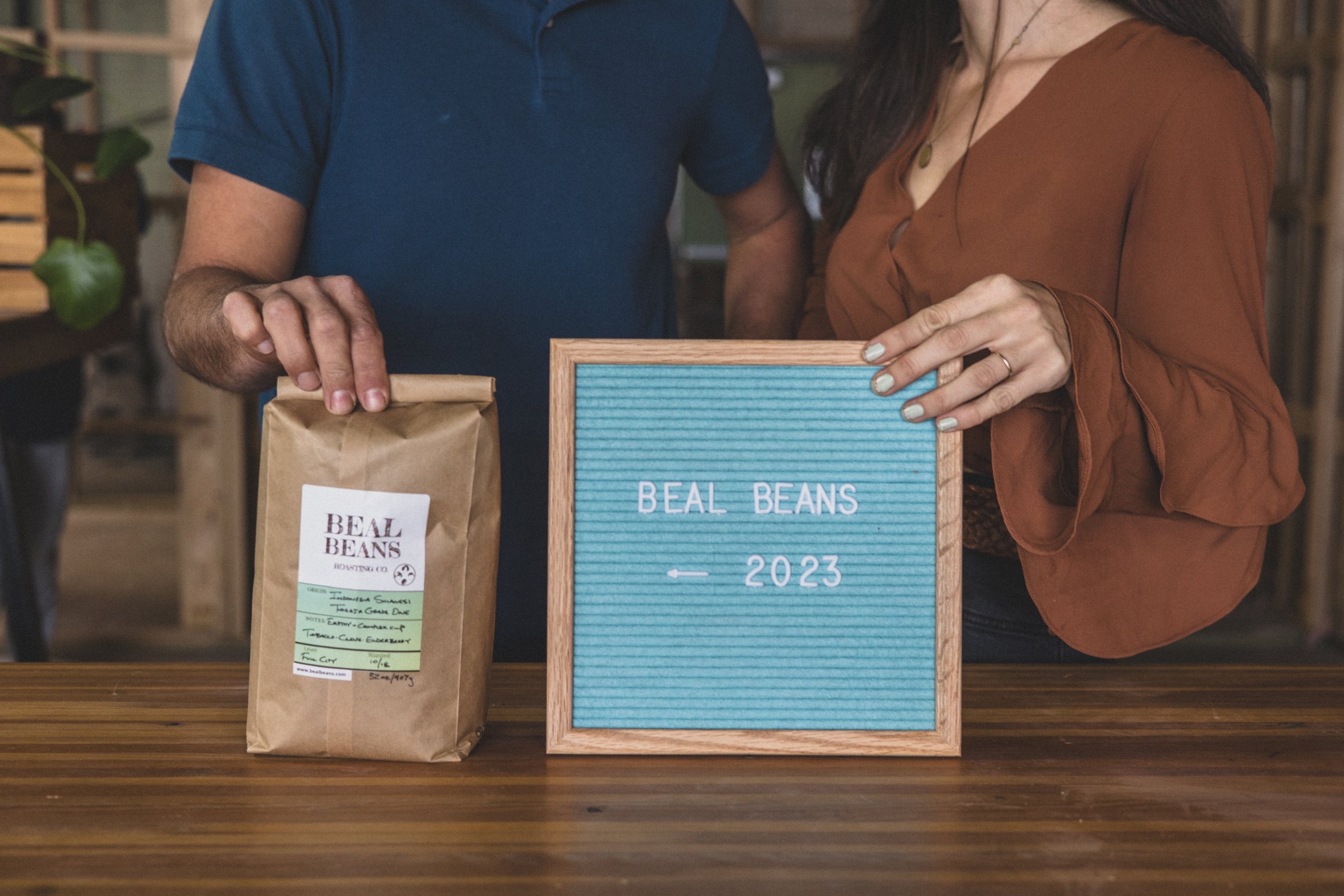 Couple poses with bag of Beal Beans fresh roasted coffee in the unfinished Beal Beans’ new coffee shop coming to Sunnyslope, AZ by Arizona family photographer, Jennifer Lind Schutsky. 