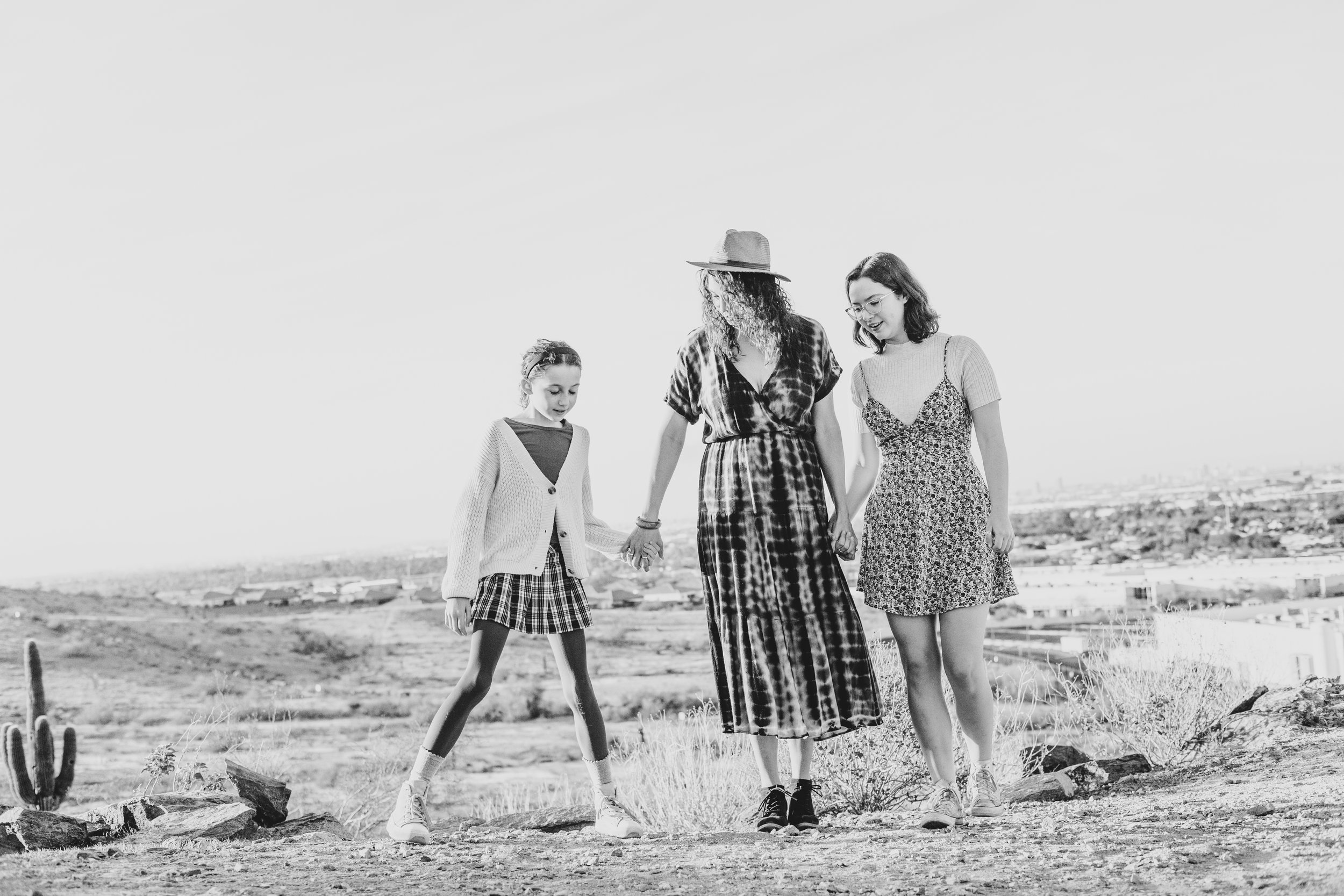 Woman and children holding hands on top of mountain boulders during their creative, lifestyle, desert family photography session with Phoenix photographer, Jennifer Lind Schutsky.