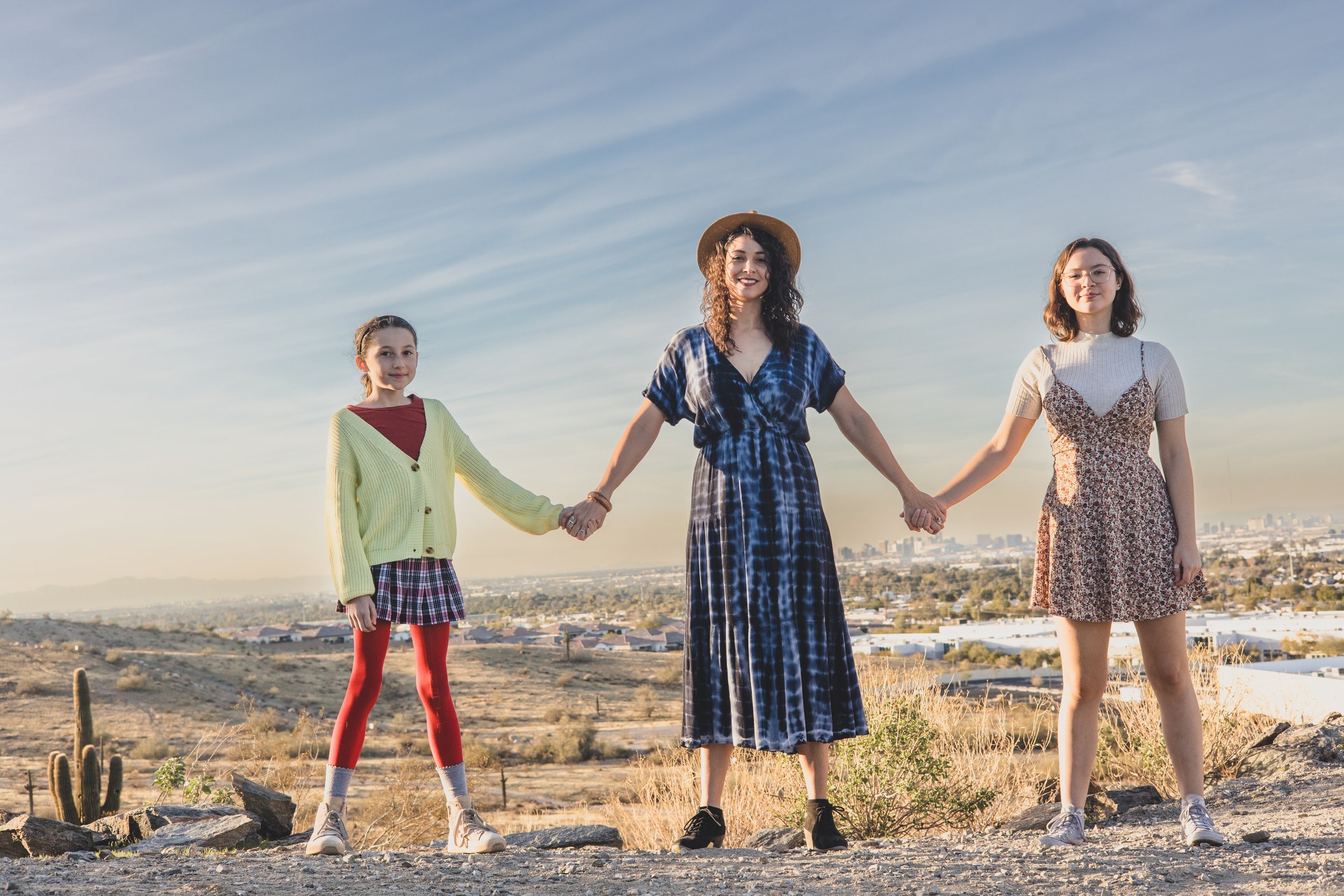 Woman and children holding hands on top of mountain boulders during their creative, lifestyle, desert family photography session with Phoenix photographer, Jennifer Lind Schutsky.