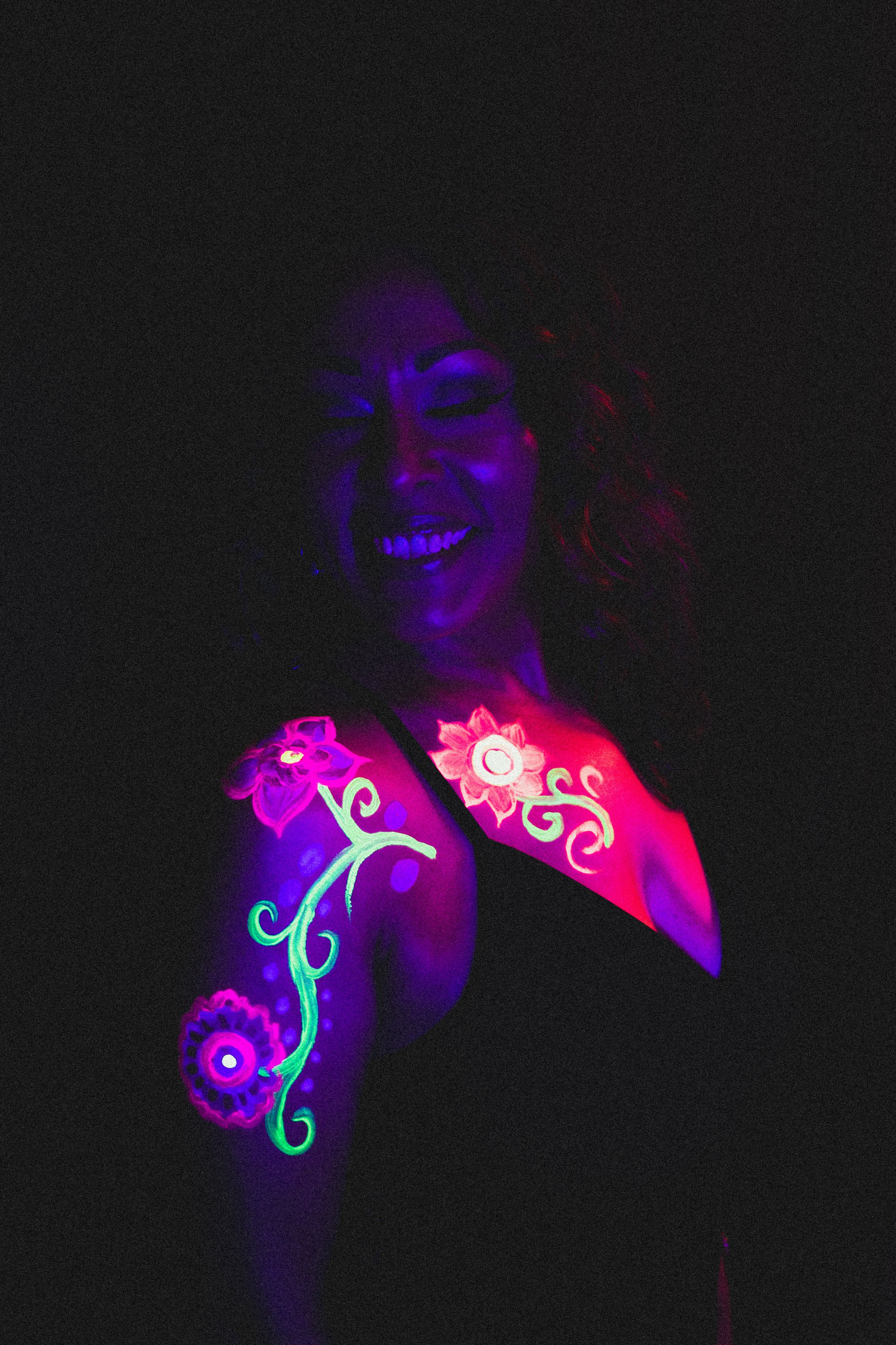 Woman poses with floral neon body paint on their face for alternative neon body painting creative photoshoot by phoenix body artist, La Luna Henna and photographer Jennifer Lind Schutsky.