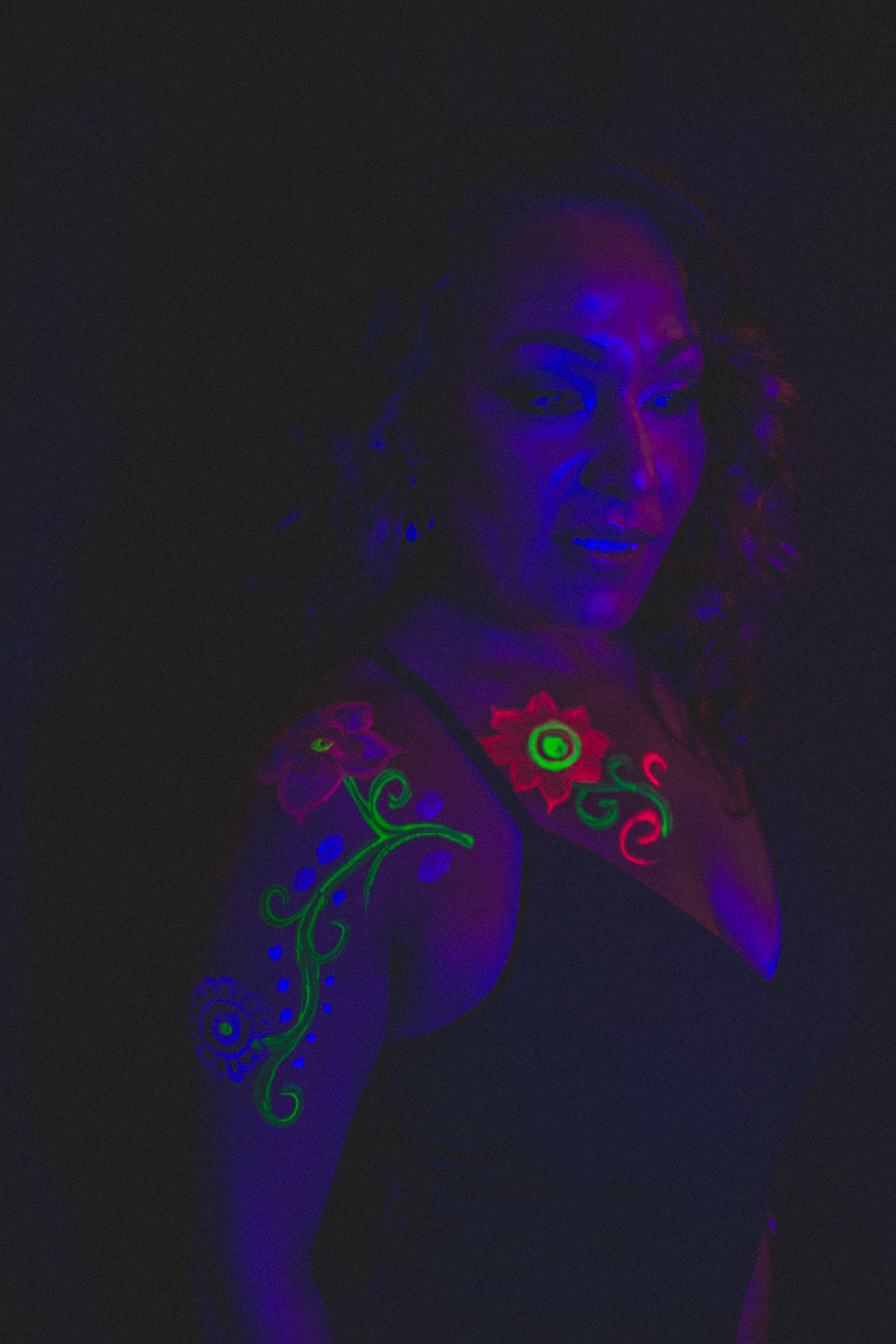 Woman poses with floral neon body paint on their face for alternative neon body painting creative photoshoot by phoenix body artist, La Luna Henna and photographer Jennifer Lind Schutsky.