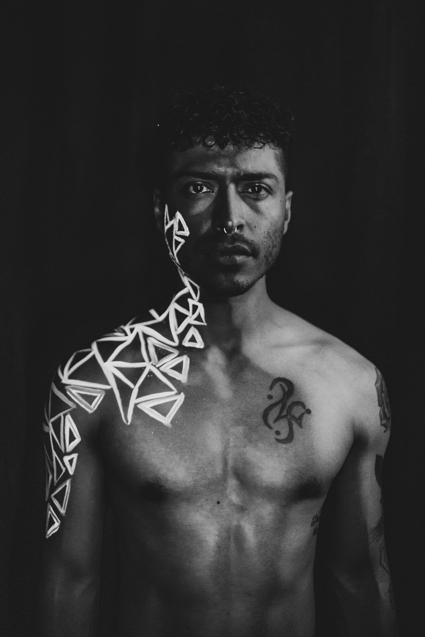 Man poses with geometric neon body paint on their face for alternative neon body painting creative photoshoot by phoenix body artist, La Luna Henna and photographer Jennifer Lind Schutsky.