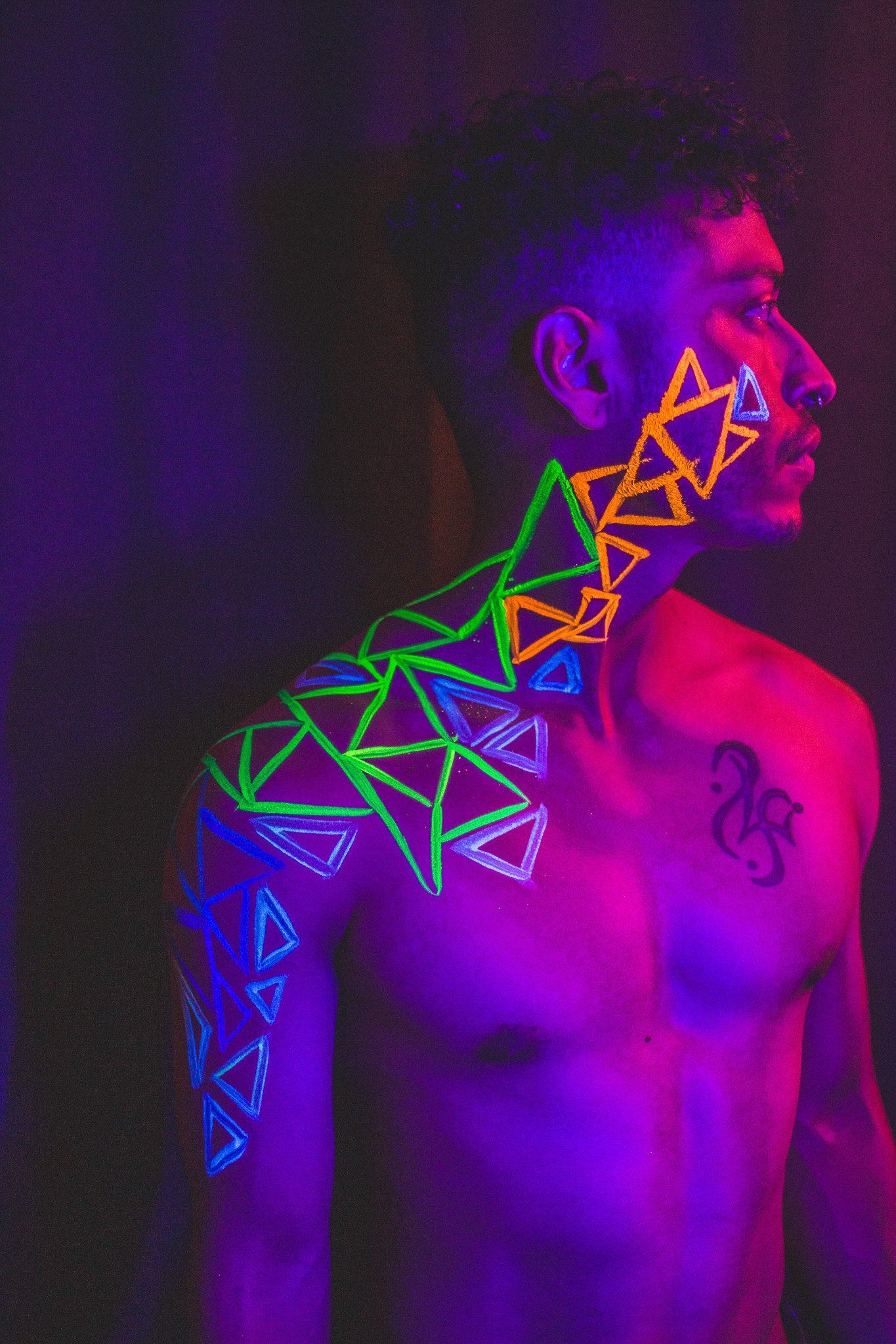 Man poses with geometric neon body paint on their face for alternative neon body painting creative photoshoot by phoenix body artist, La Luna Henna and photographer Jennifer Lind Schutsky.