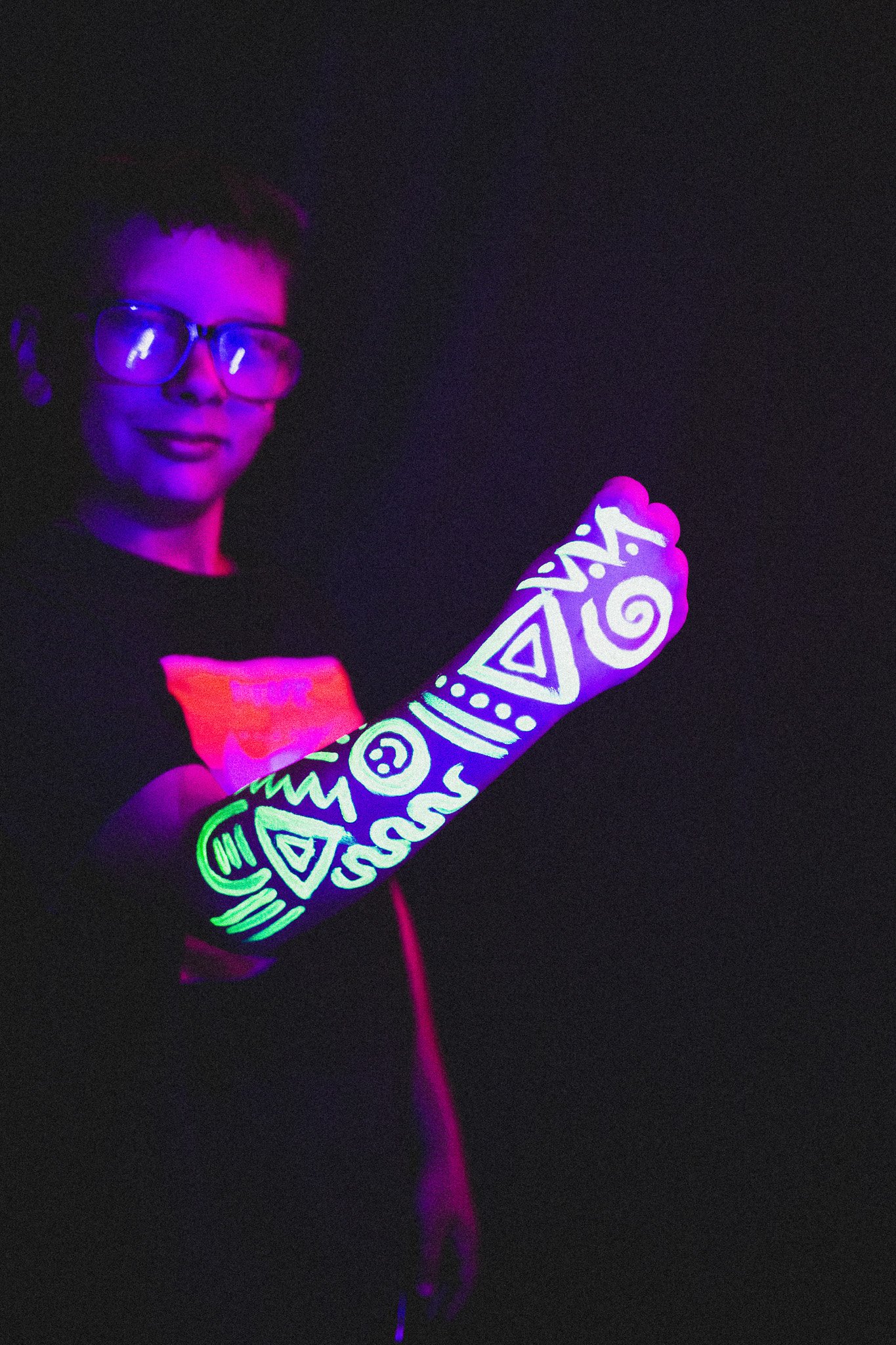 Kid poses with geometric neon body paint on their arm for alternative neon body painting creative photoshoot by phoenix body artist, La Luna Henna and photographer Jennifer Lind Schutsky.