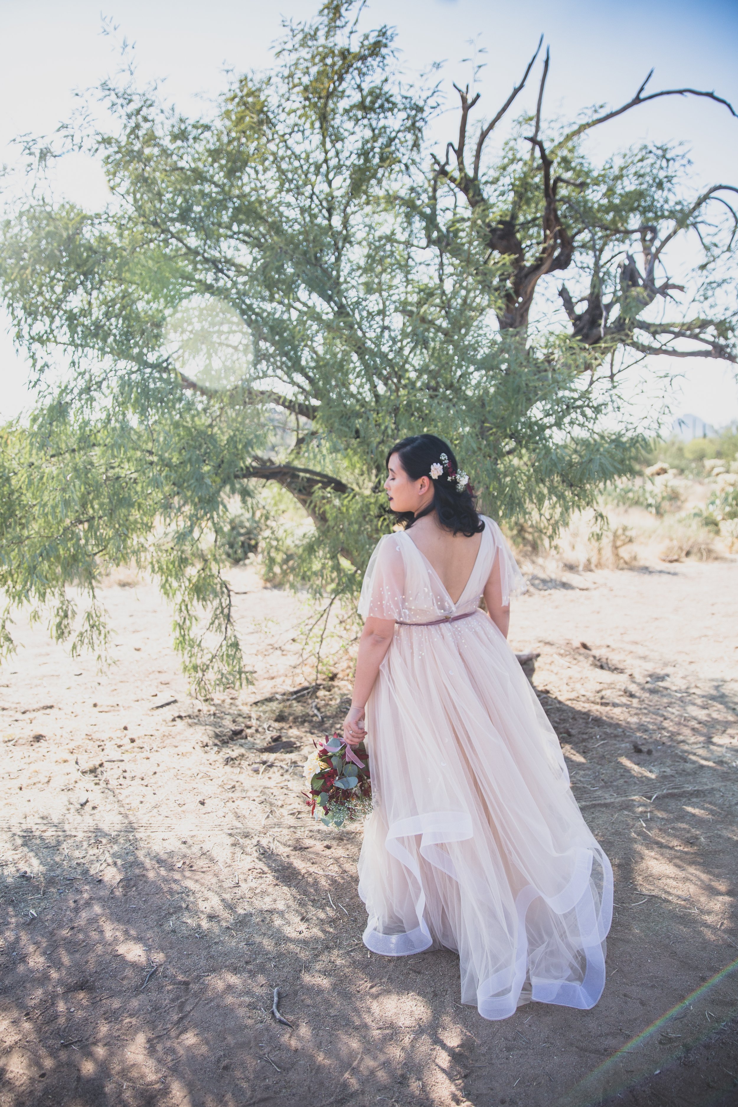 Bride and her wildflower floral bouquet pose for her intimate Superstition Mountains micro wedding near Phoenix, Arizona by wilderness wedding photographer, Jennifer Lind Schutsky. 