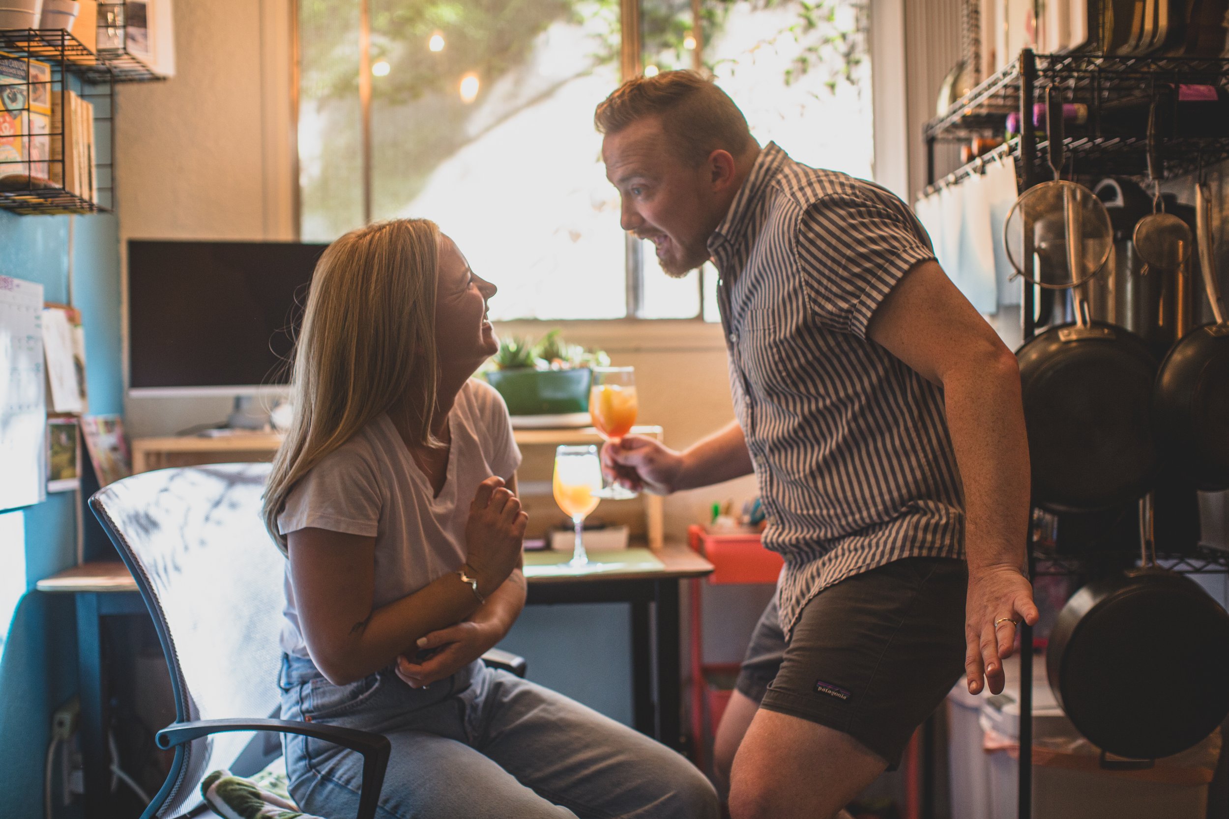 Adorable couple laugh on countertop during their in-home engagement photo session with Phoenix based creative wedding photographer; Jennifer Lind Schutsky. 