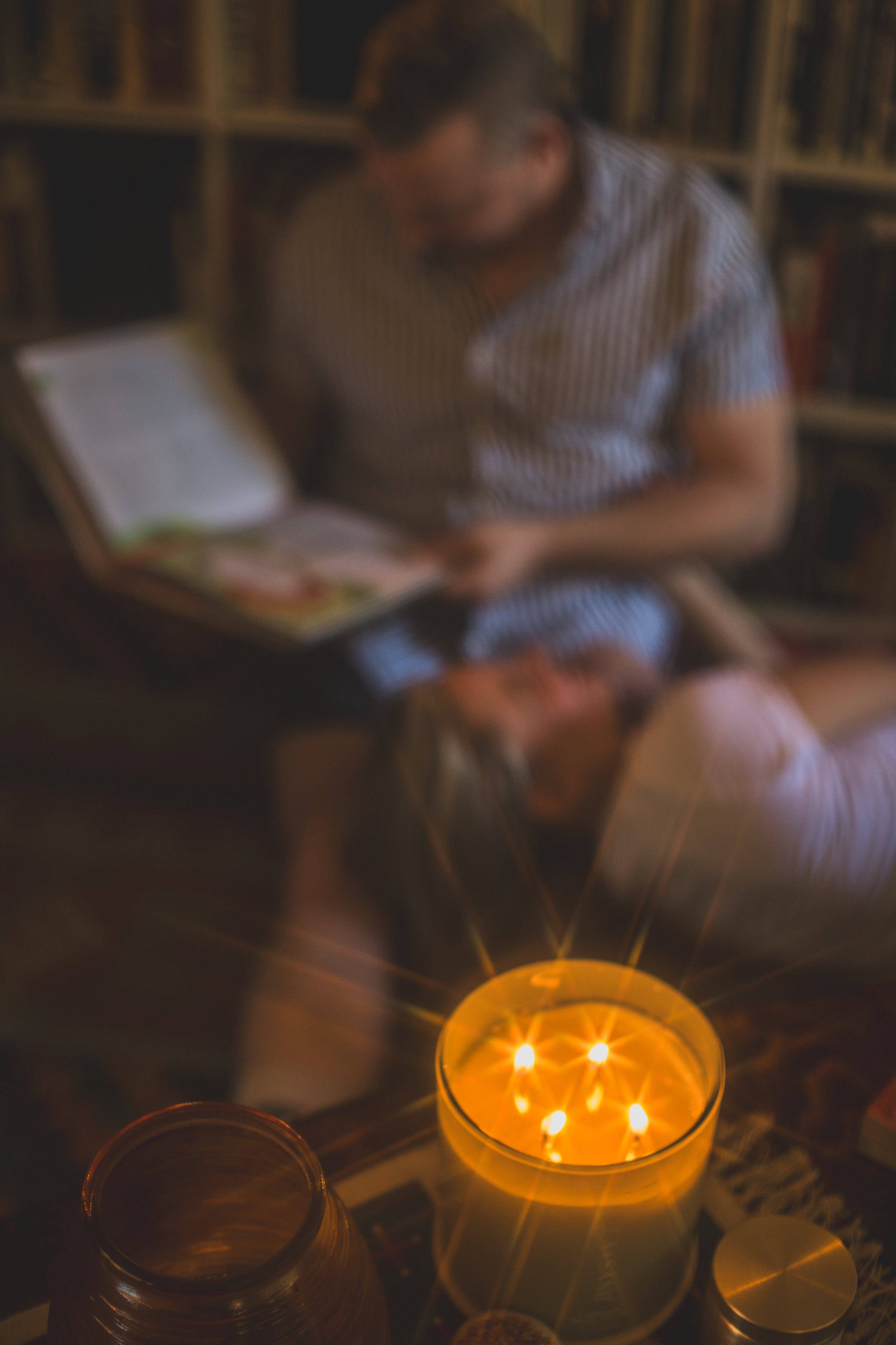 Candle detail as couple cuddles for a pose during their In-home engagement photo session with creative lifestyle photographer; Jennifer Lind Schutsky. 