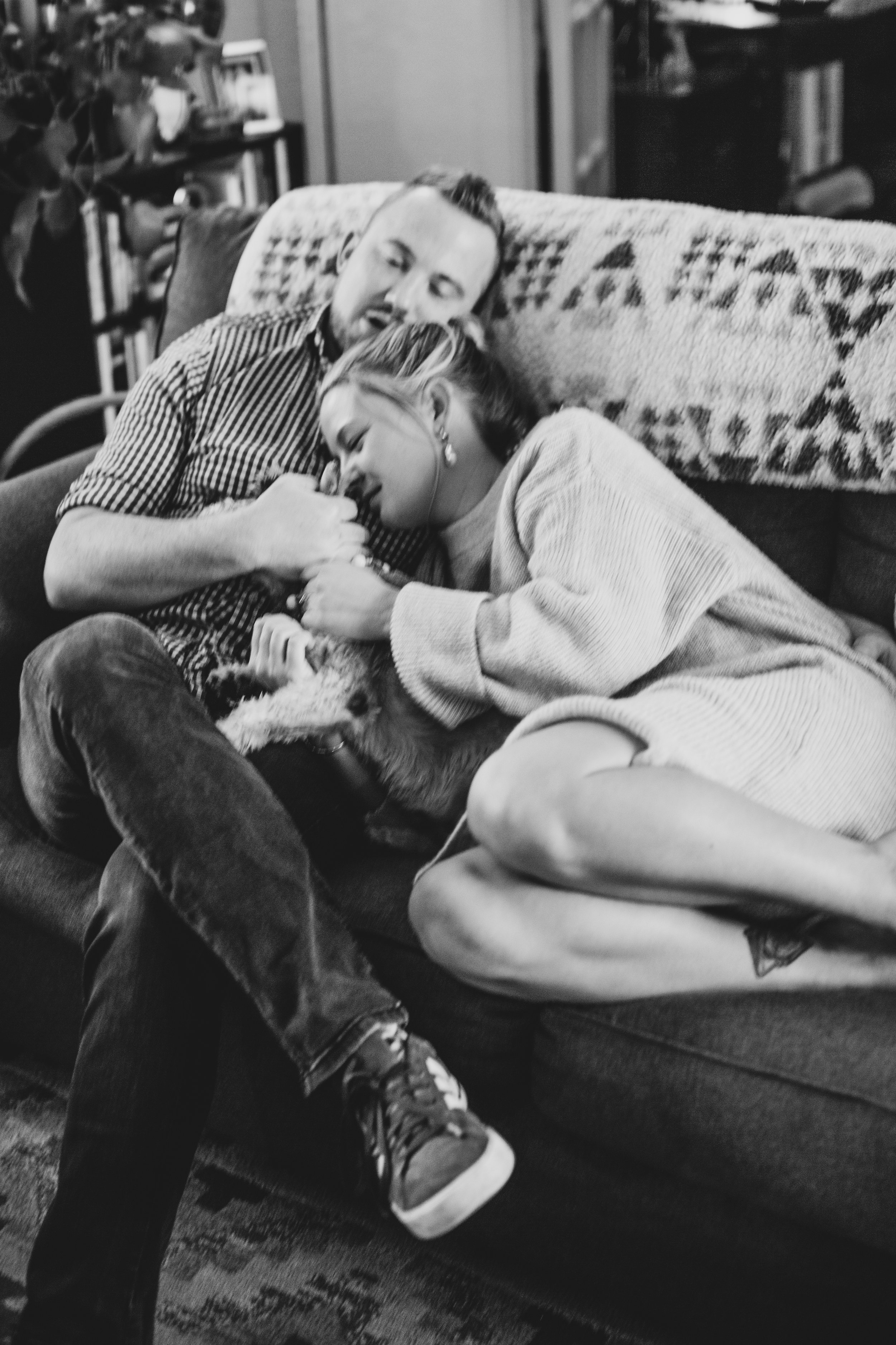 Couple sits cuddling on the couch during their in-home engagement photo session with Phoenix based creative wedding photographer; Jennifer Lind Schutsky. 
