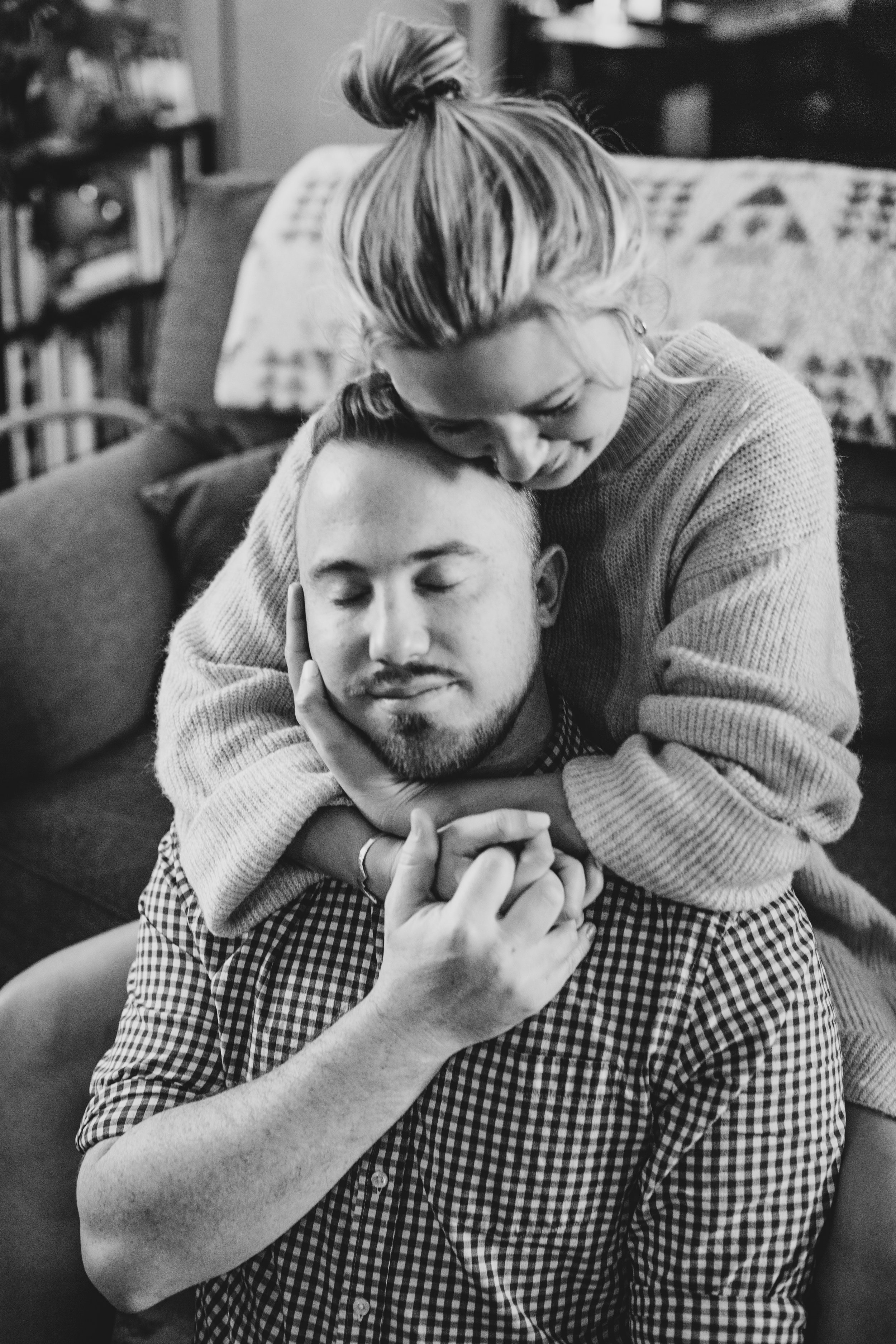 Couple sits cuddling on the couch during their in-home engagement photo session with Phoenix based creative wedding photographer; Jennifer Lind Schutsky. 