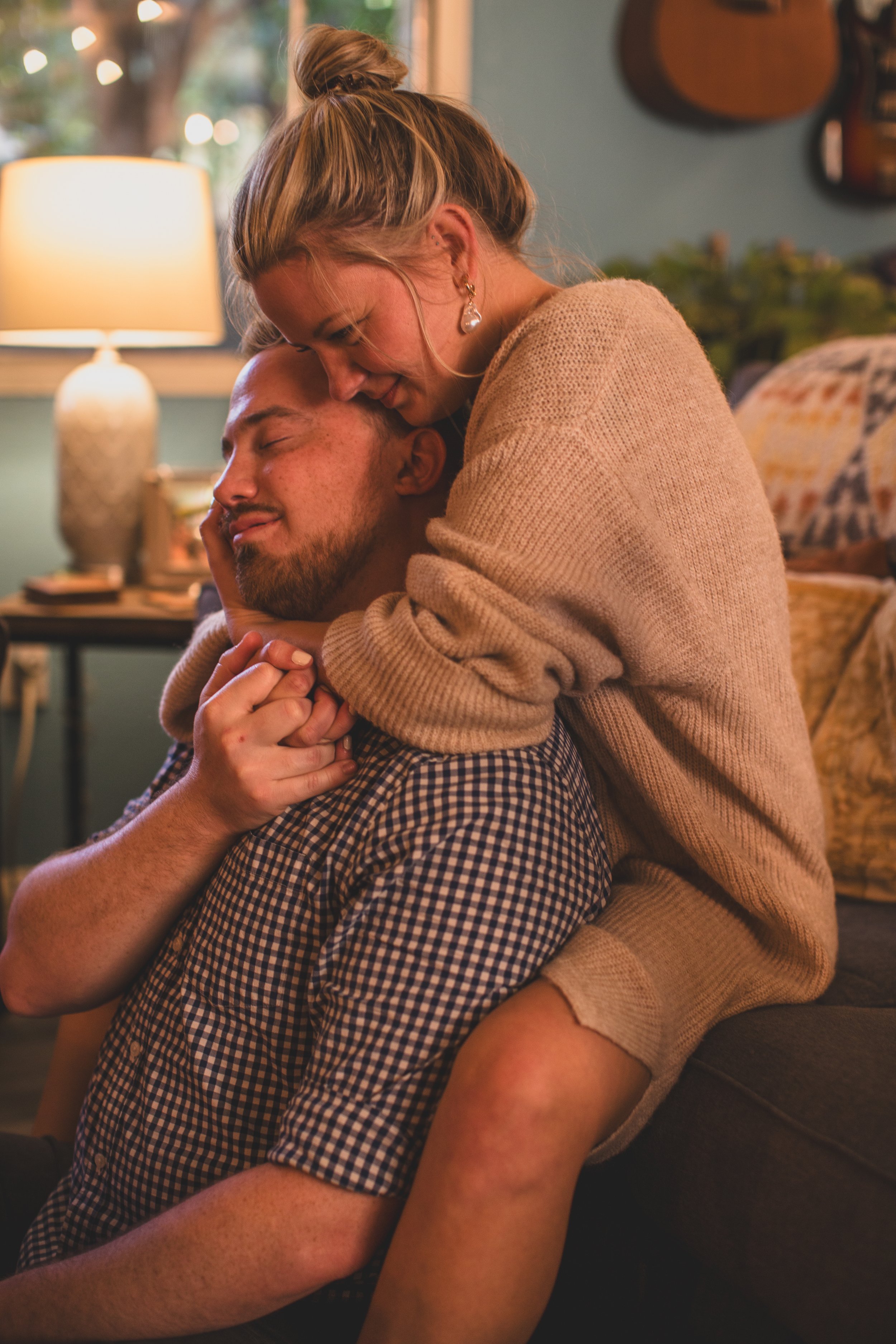 Couple sits cuddling on the couch during their in-home engagement photo session with Phoenix based creative wedding photographer; Jennifer Lind Schutsky. 