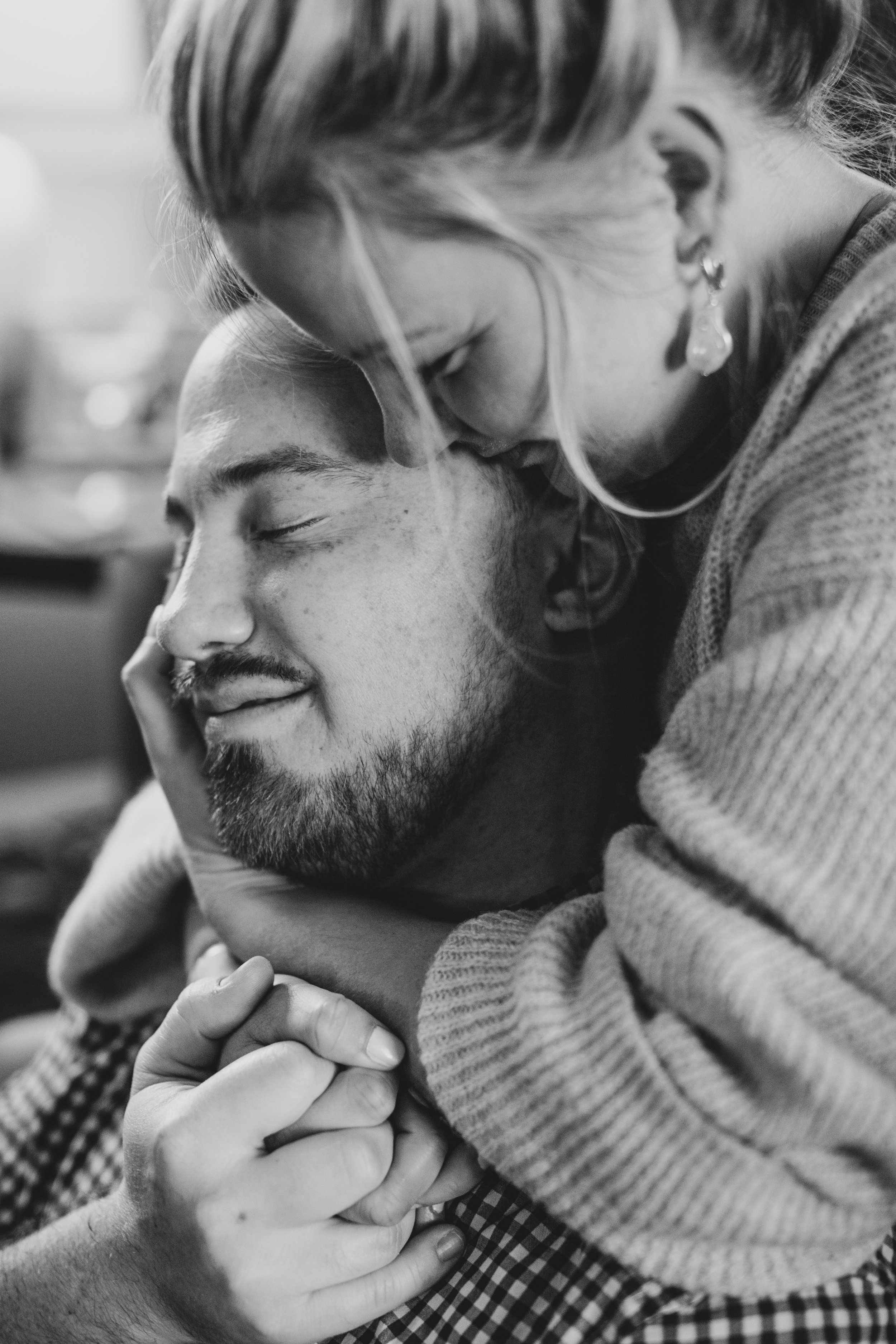 Couple sits cuddling on the couch during their in-home engagement photo session with Phoenix based creative wedding photographer; Jennifer Lind Schutsky. 