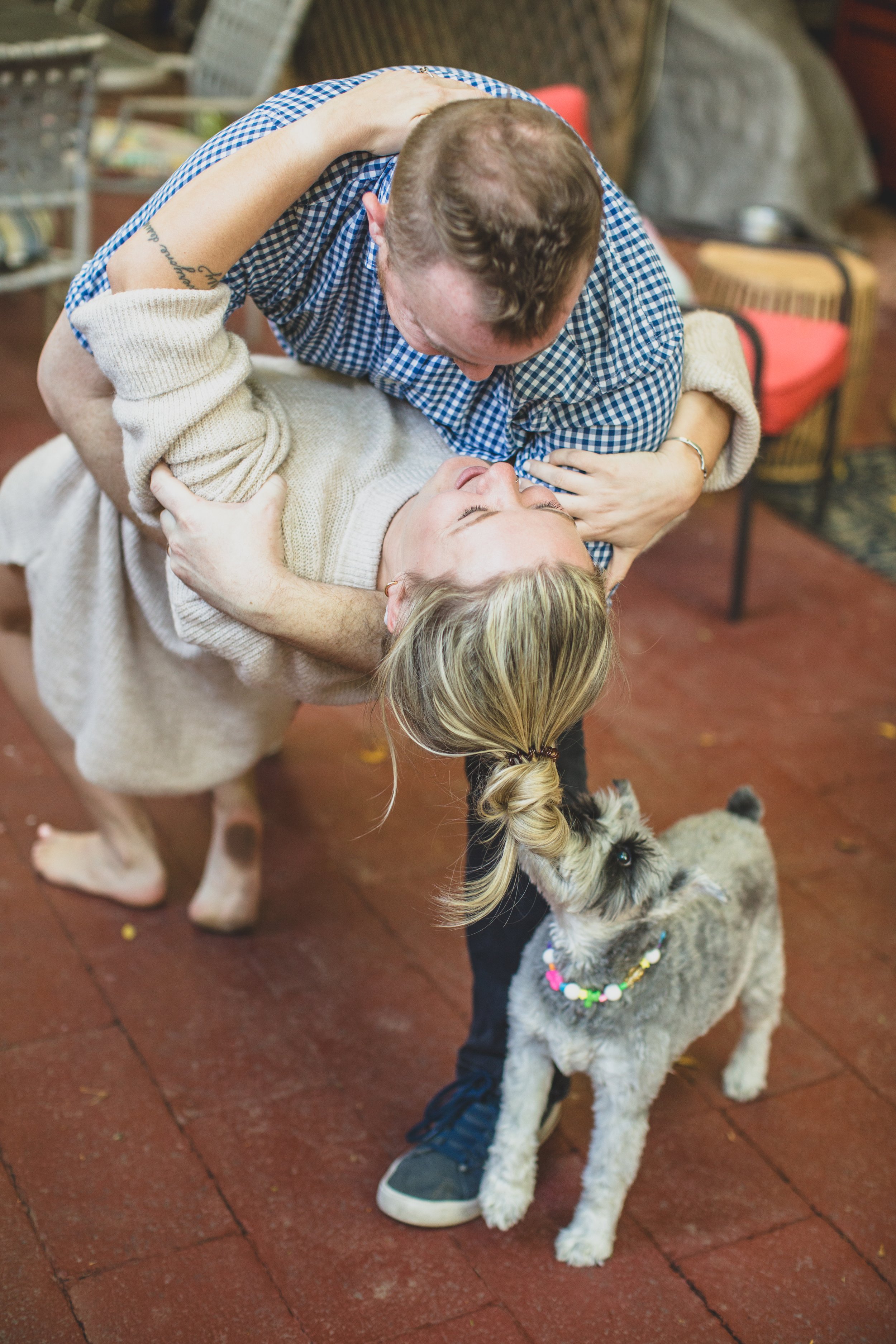 Couple dances with their dog during their in-home engagement photo session with creative lifestyle photographer; Jennifer Lind Schutsky. 