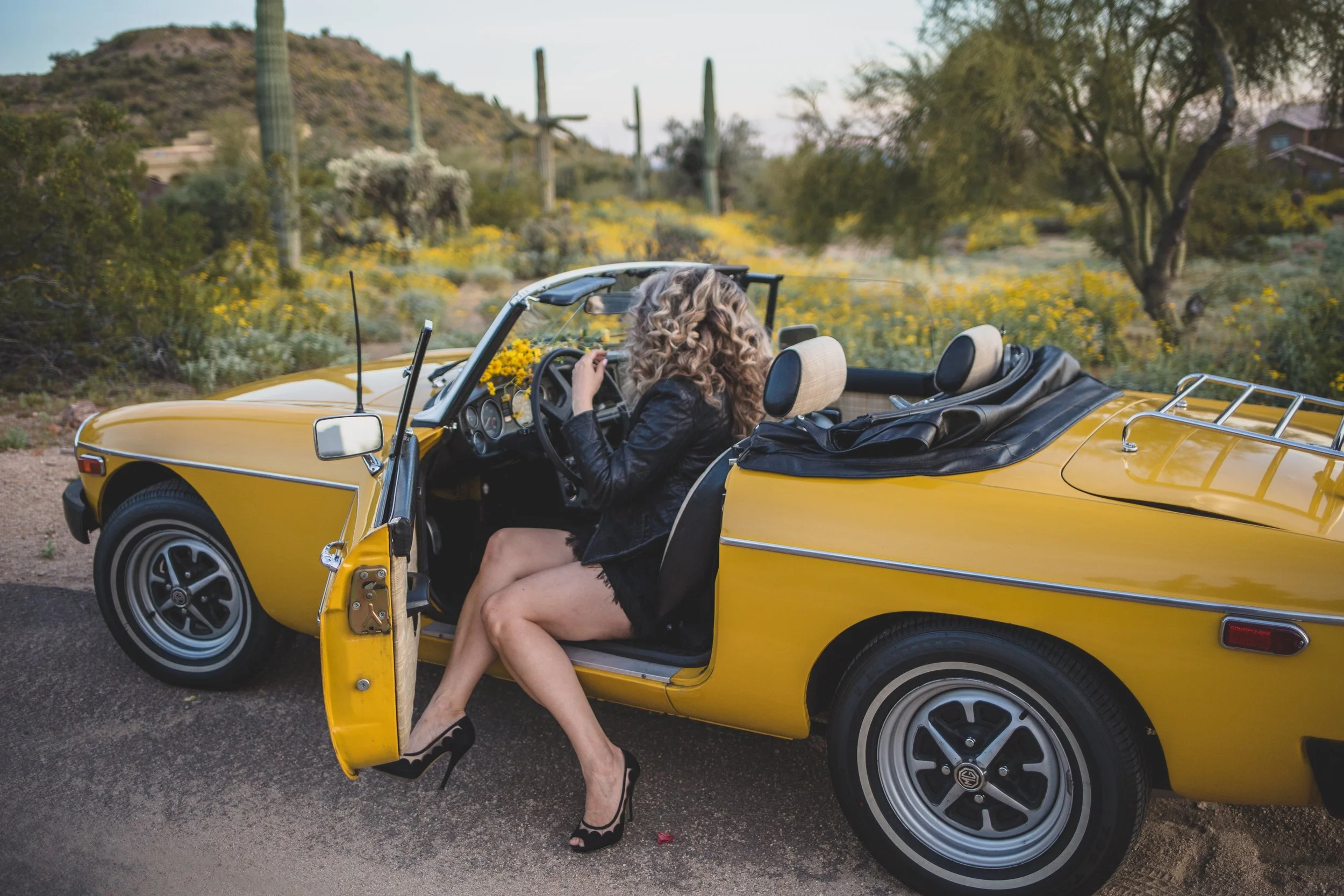Breast Cancer Survivor poses for breast cancer survivor photoshoot with yellow MG sports car in Arizona desert with Phoenix Creative Photographer; Jennifer Lind Schutsky.
