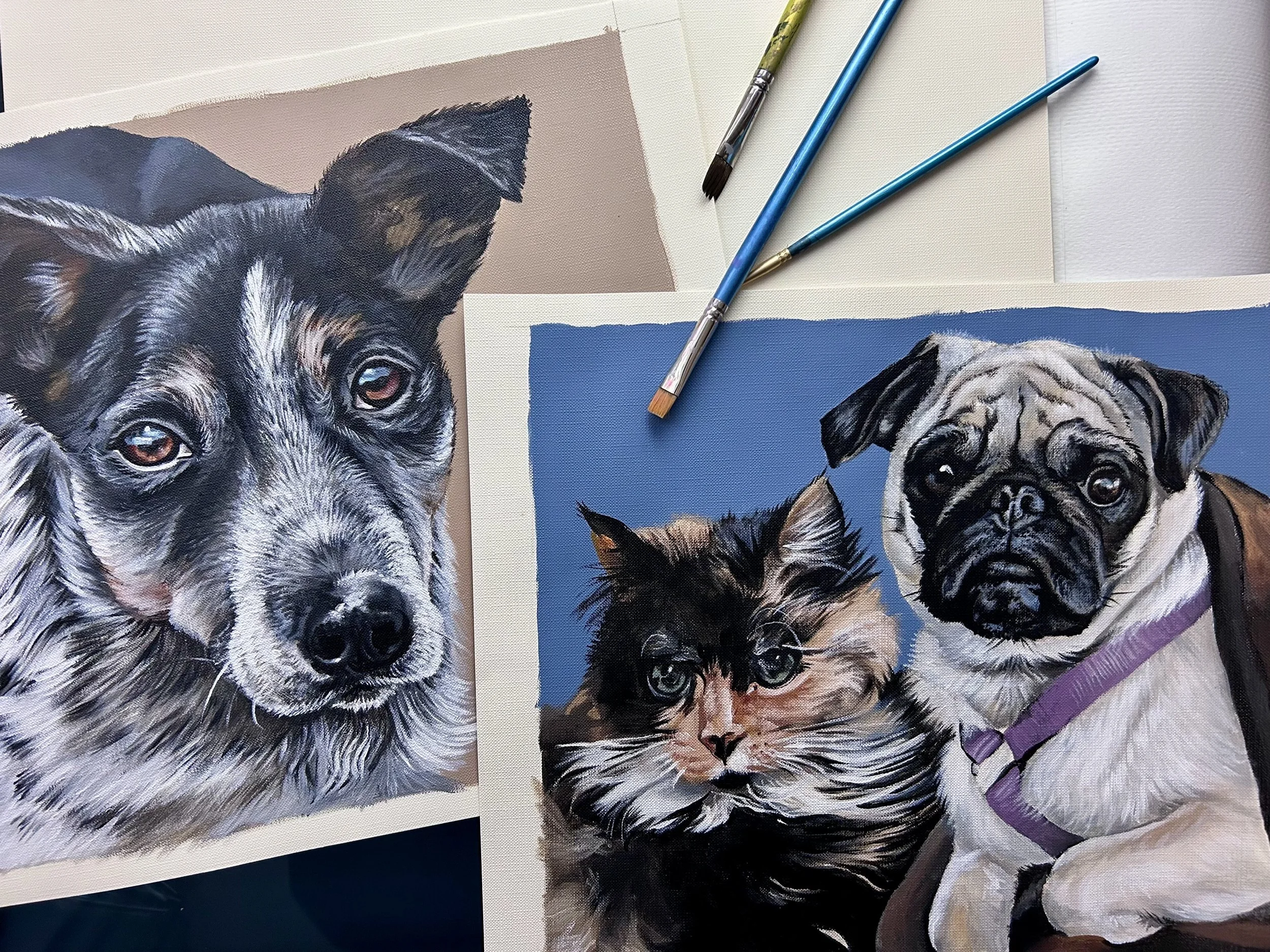 Artwork of a dog, a cat, and a pug. The dog is a black and gray mixed breed, the cat is a long-haired calico, and the pug has a wrinkled face with a purple harness. Painting supplies are placed above.