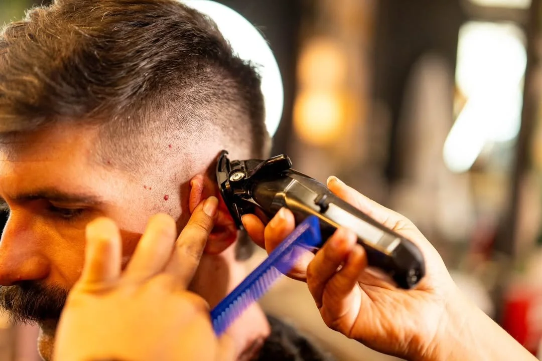 Barber using clippers to blend short sides beneath a textured top at Barbon's Barbershop.