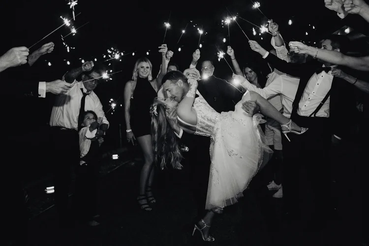 Wedding guests holding sparklers form a tunnel as the bride is carried through at the end of a Los Angeles reception