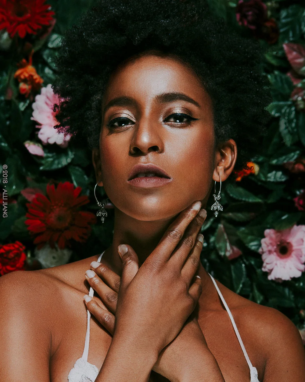Editorial studio portrait framed by dark red and pink florals