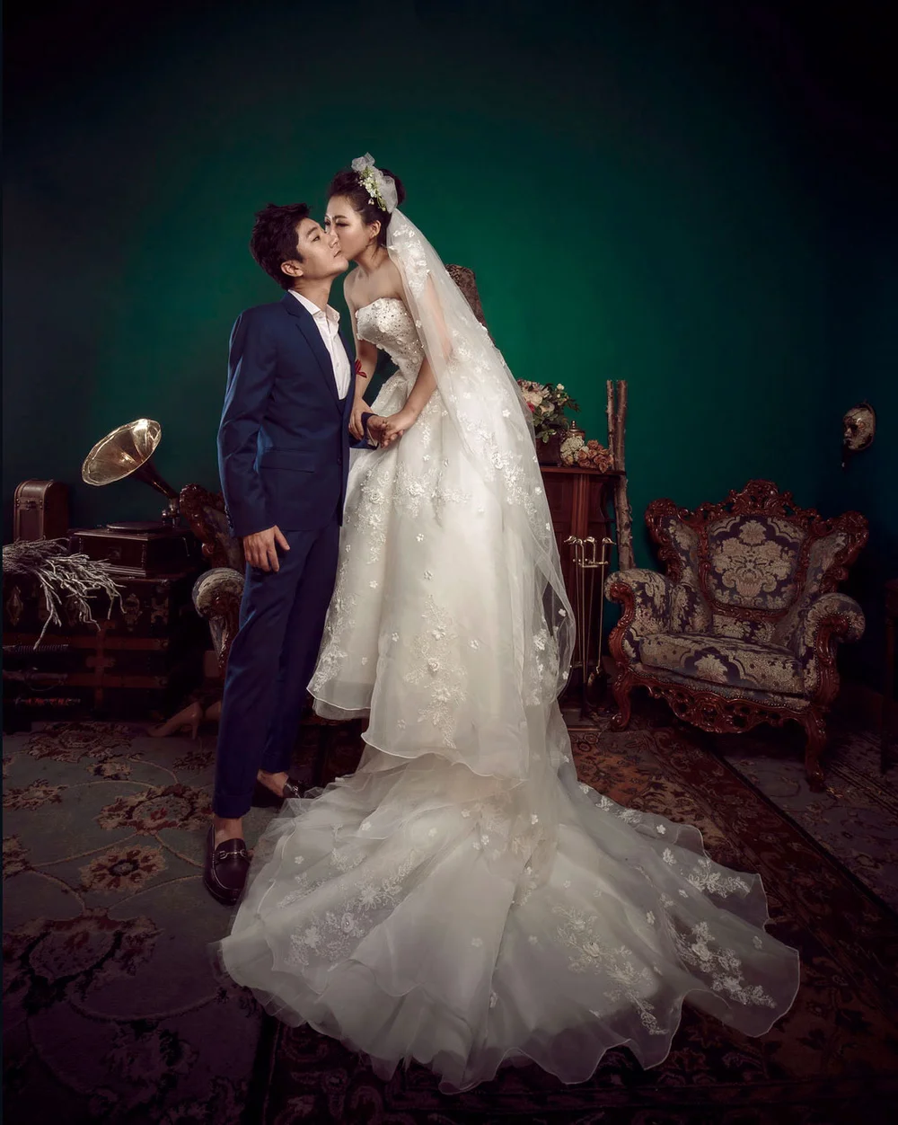 Fine art portrait of a couple against a deep green painted backdrop