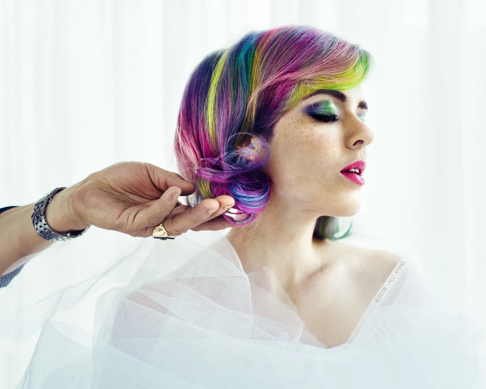 A stylist finishing rainbow hair before a creative portrait session