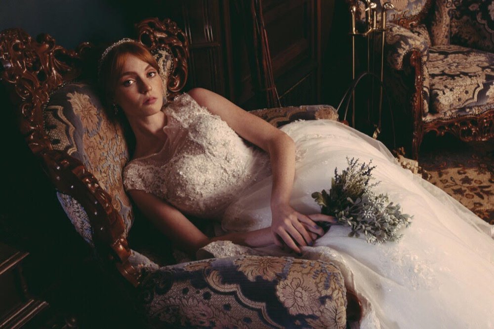 Oil-painting style portrait of a bride reclining on an antique chaise