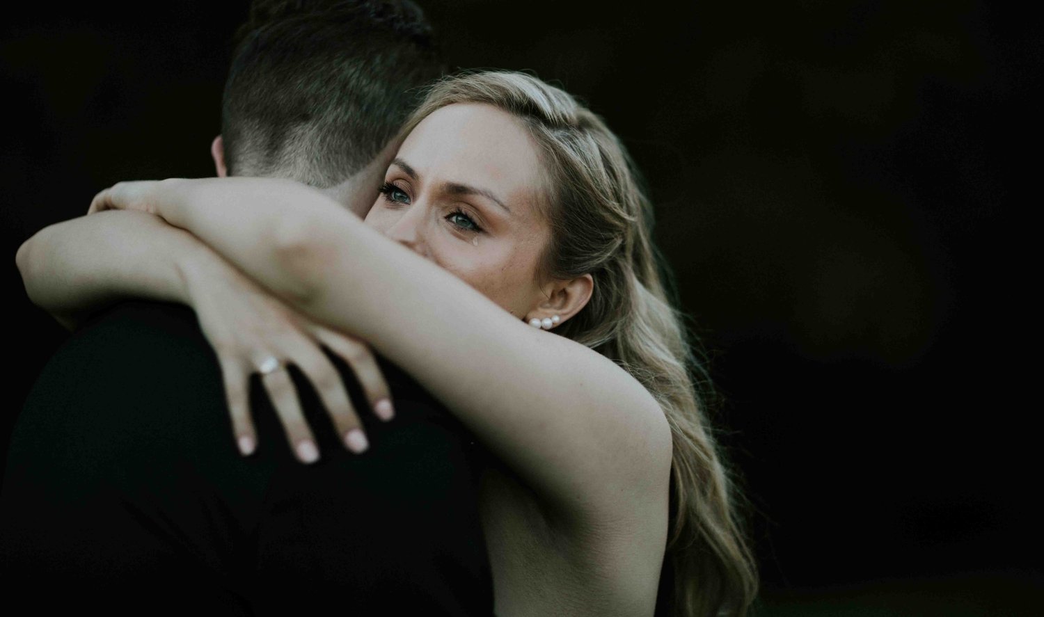 Bride embracing a guest closely, her hands clasped behind his shoulders
