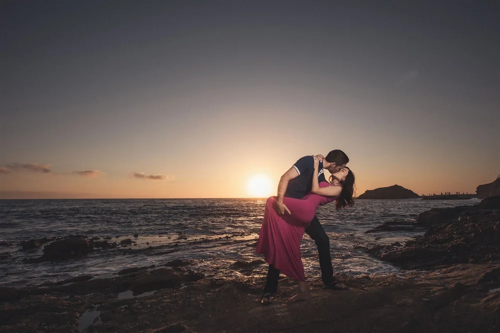 Engaged couple dancing on the rocks at sunset during a Laguna Beach engagement session