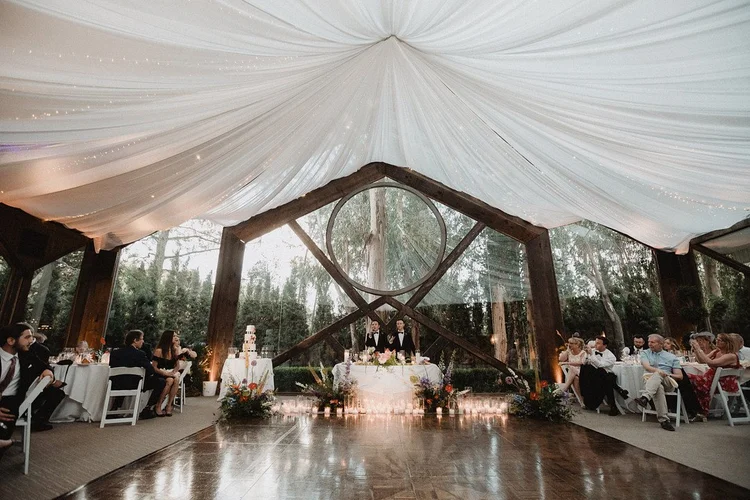 Draped reception tent lit with warm string lights before the guests arrive
