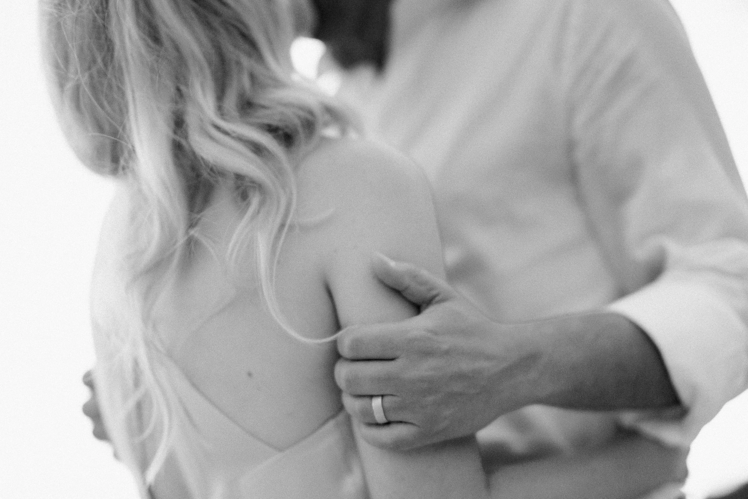 A couple in white holding each other close in warm afternoon light