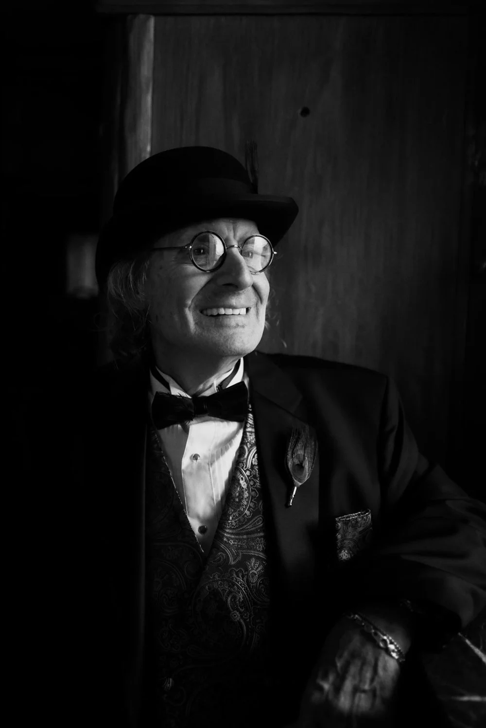 A wedding guest in a bowler hat lit only by a doorway, photographed on fast black and white film with no added light