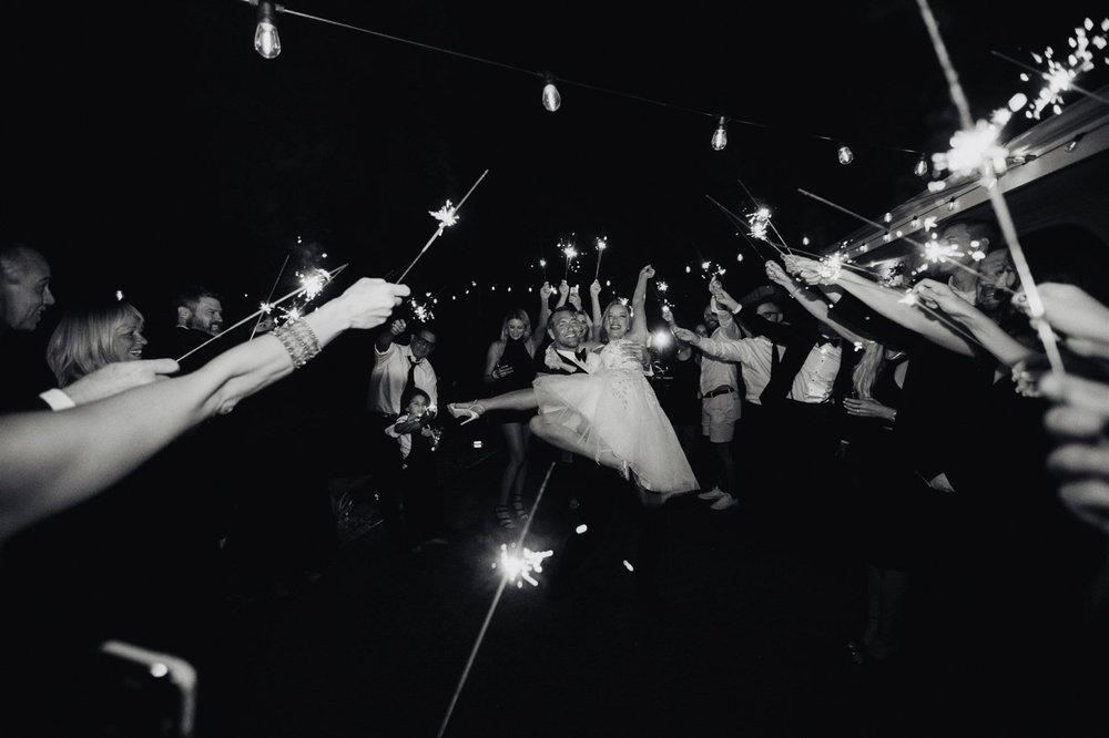 Wedding guests raising sparklers overhead for the send-off at night