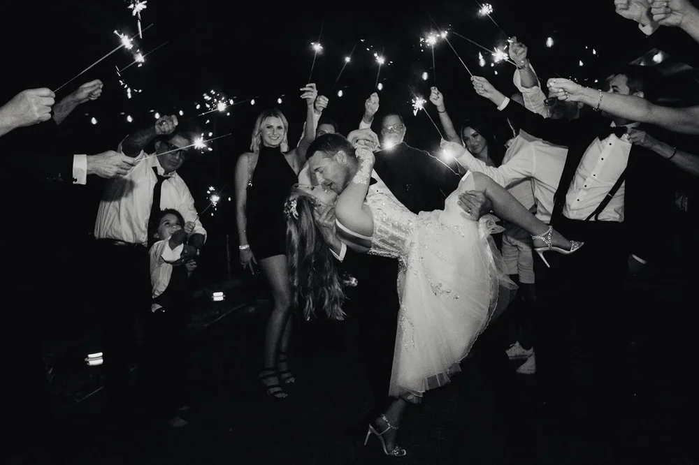 Bride and groom dipping for a kiss inside a tunnel of sparklers
