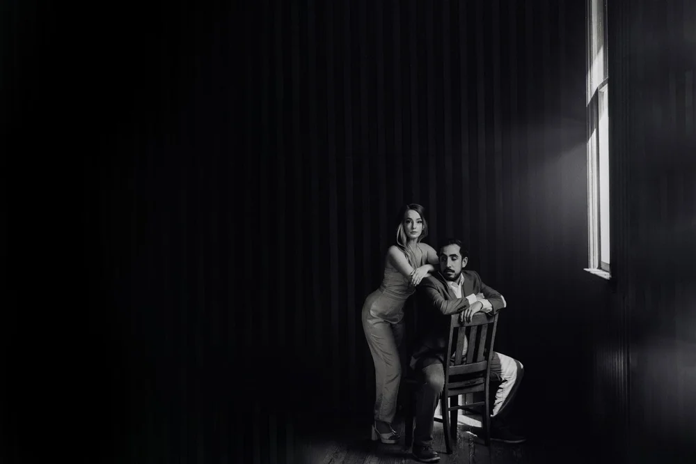 Couple in a single pool of light in a large, dark room