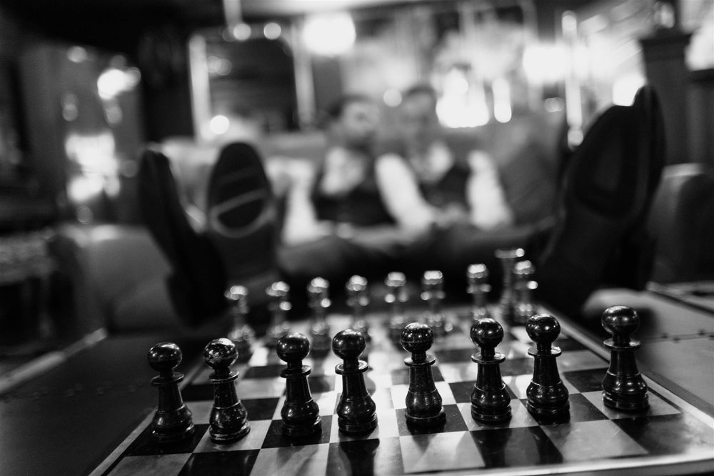Chess set on a table at the reception, guests behind, black and white