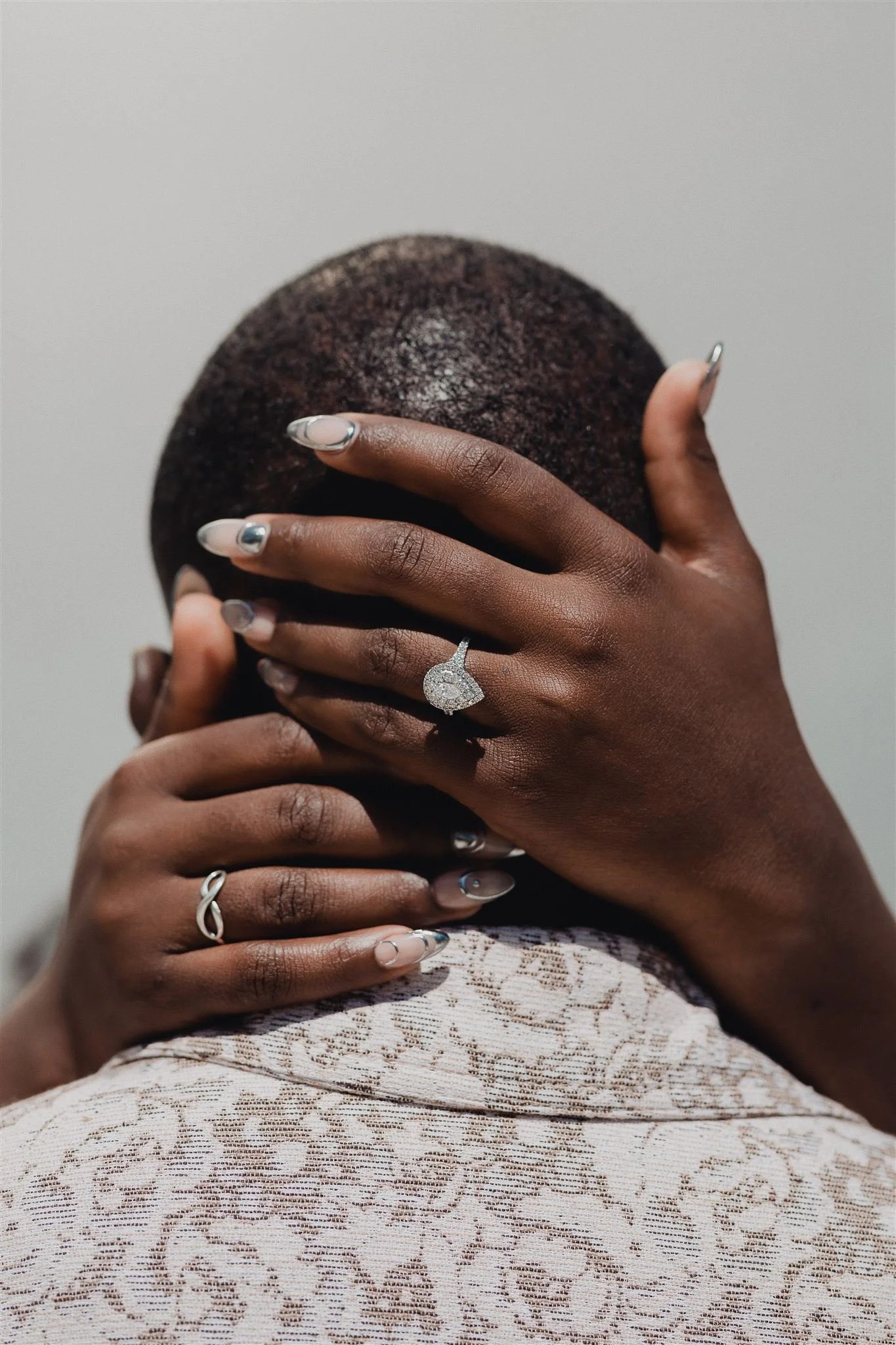 Bride's hands with her engagement ring resting on the groom's head