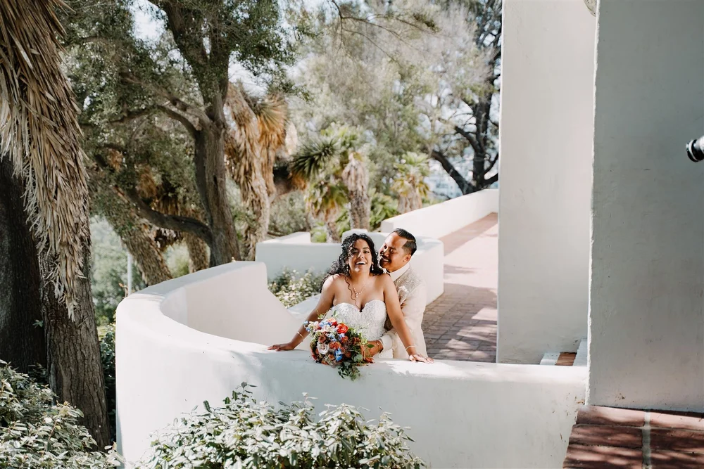 Bride and groom on a curved white staircase surrounded by greenery