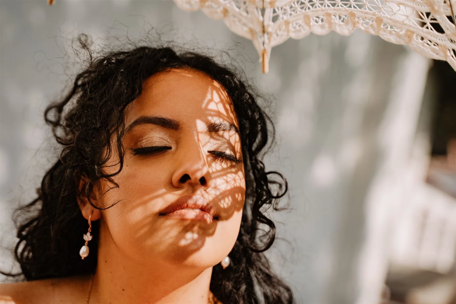 Bride with the dappled shadow of a lace parasol falling across her face